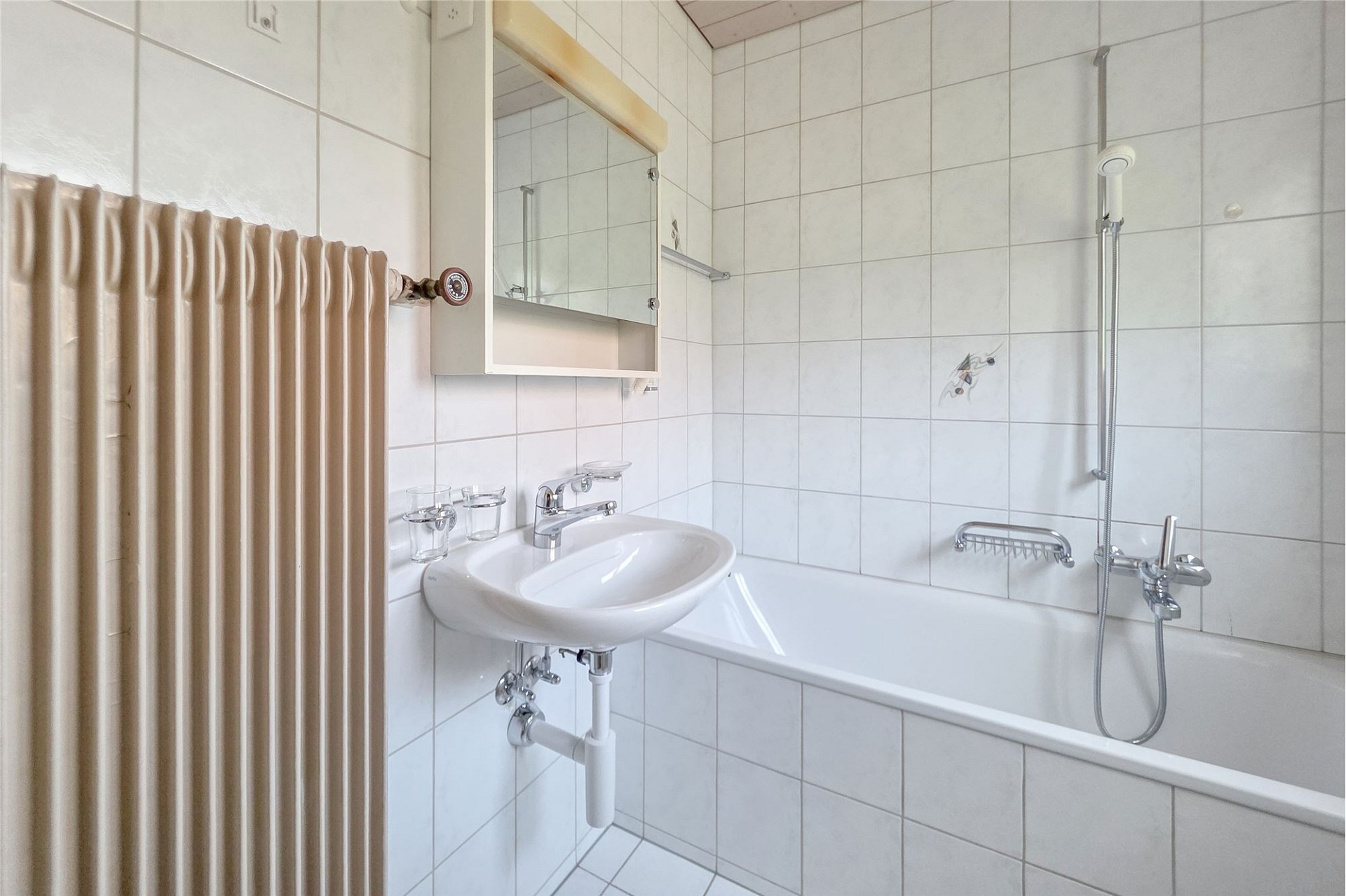 Kleines Badezimmer mit Badewanne und Waschtisch