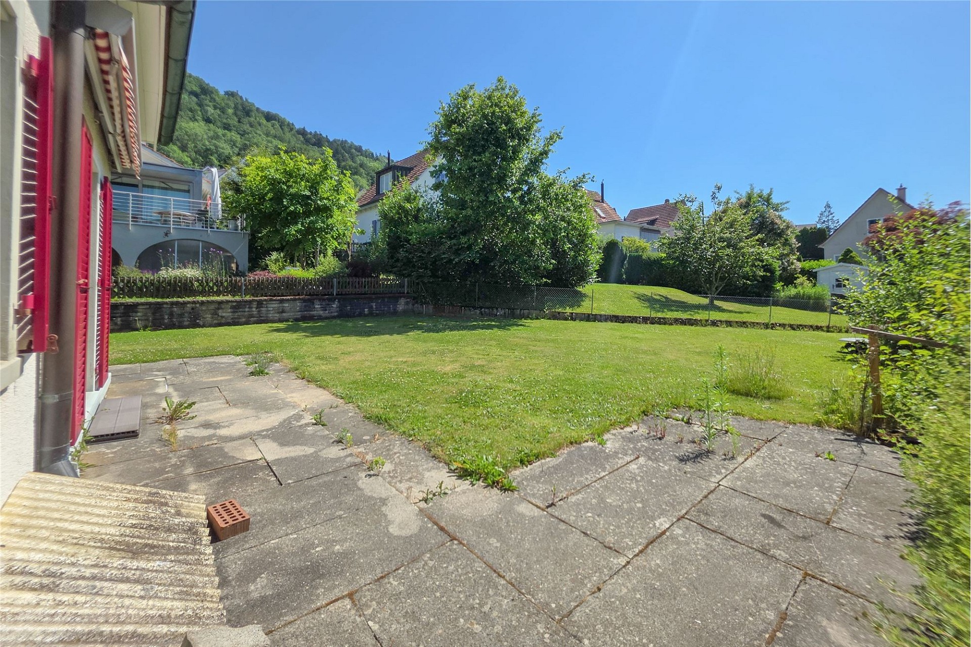 Großer Garten mit Terrasse und Wohnhäusern im Hintergrund