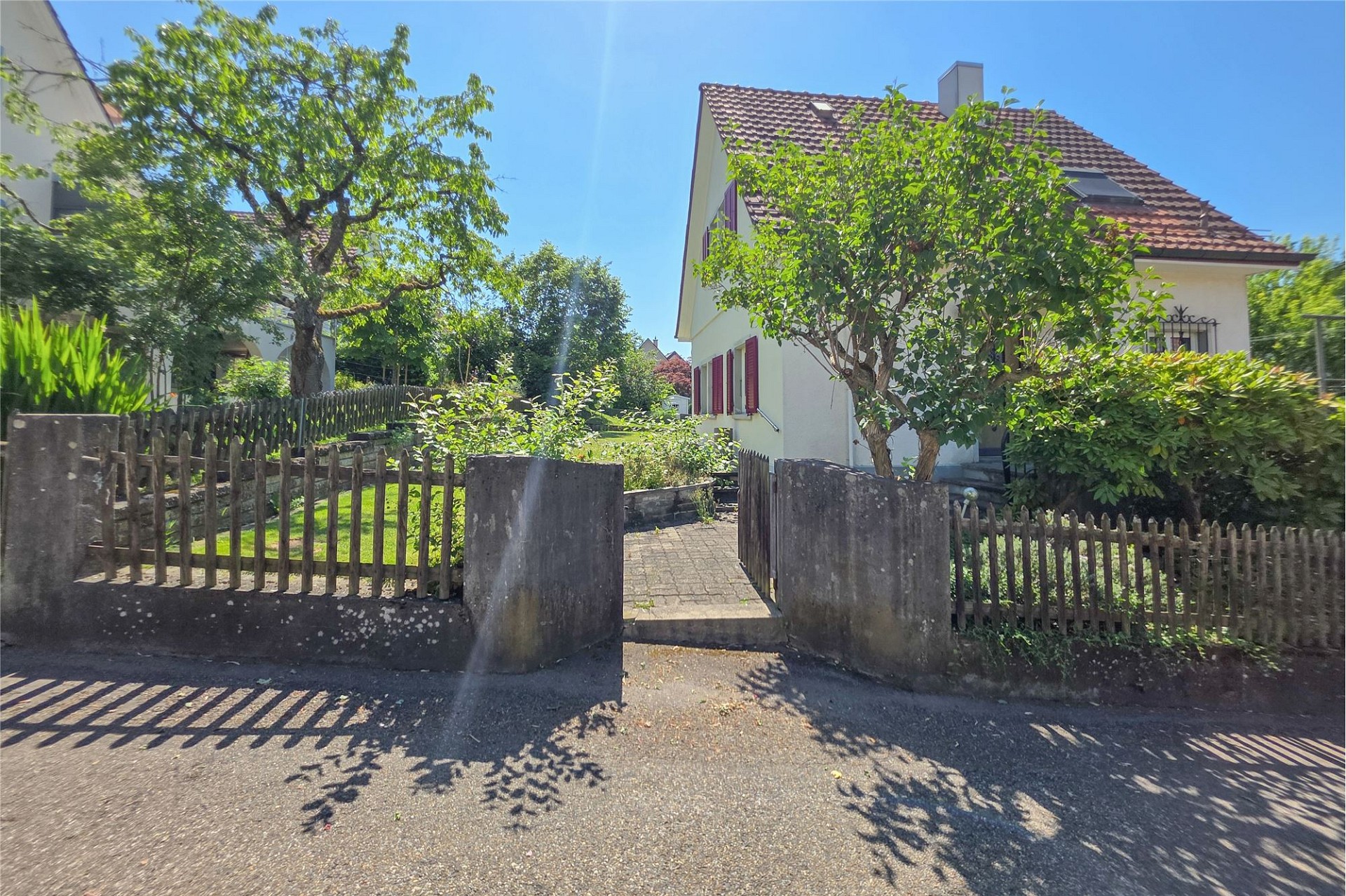 Sonnige Außenansicht eines Einfamilienhauses mit Vorgarten