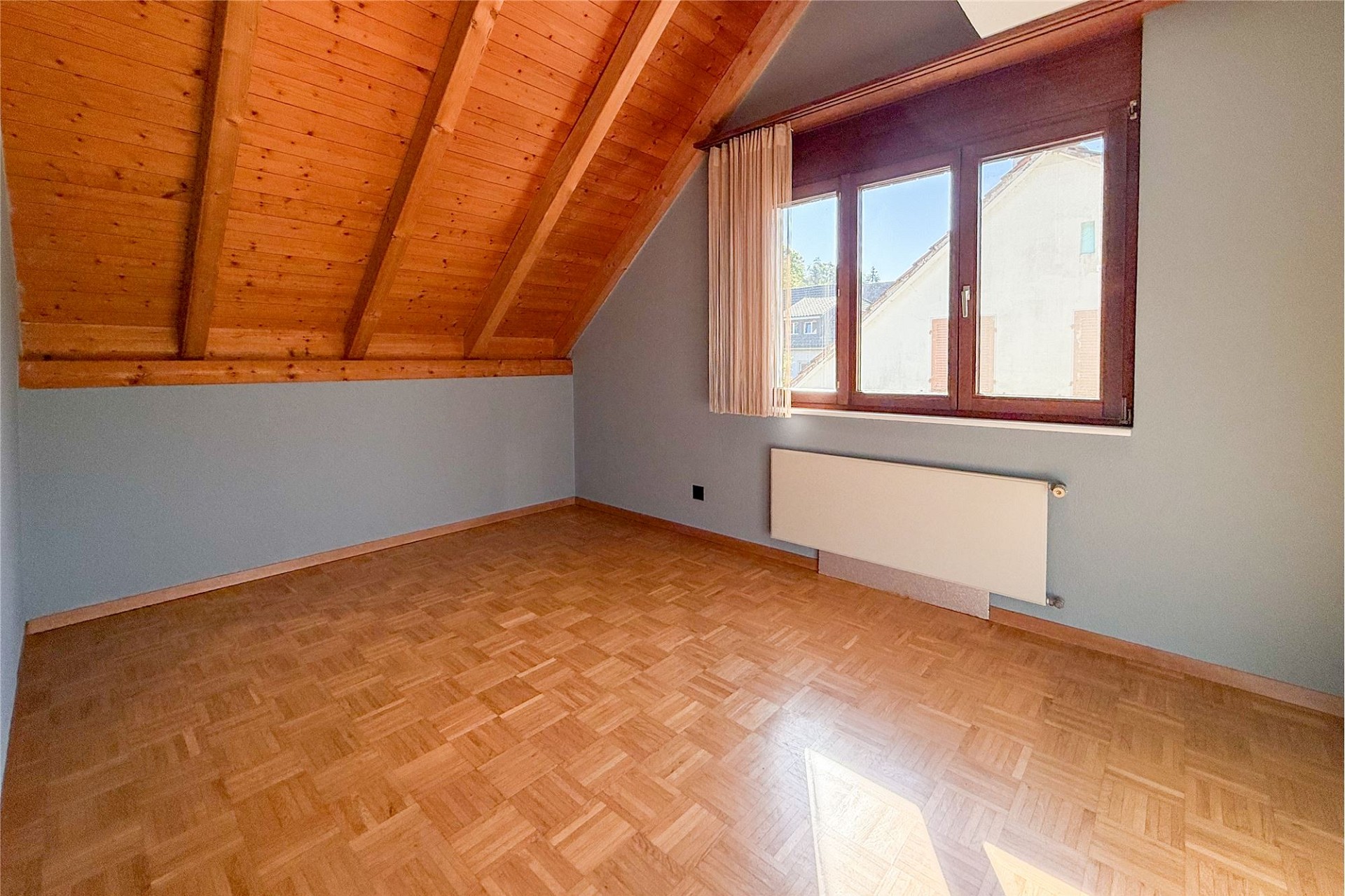 Dachgeschossraum mit Holzdecke und Fenster