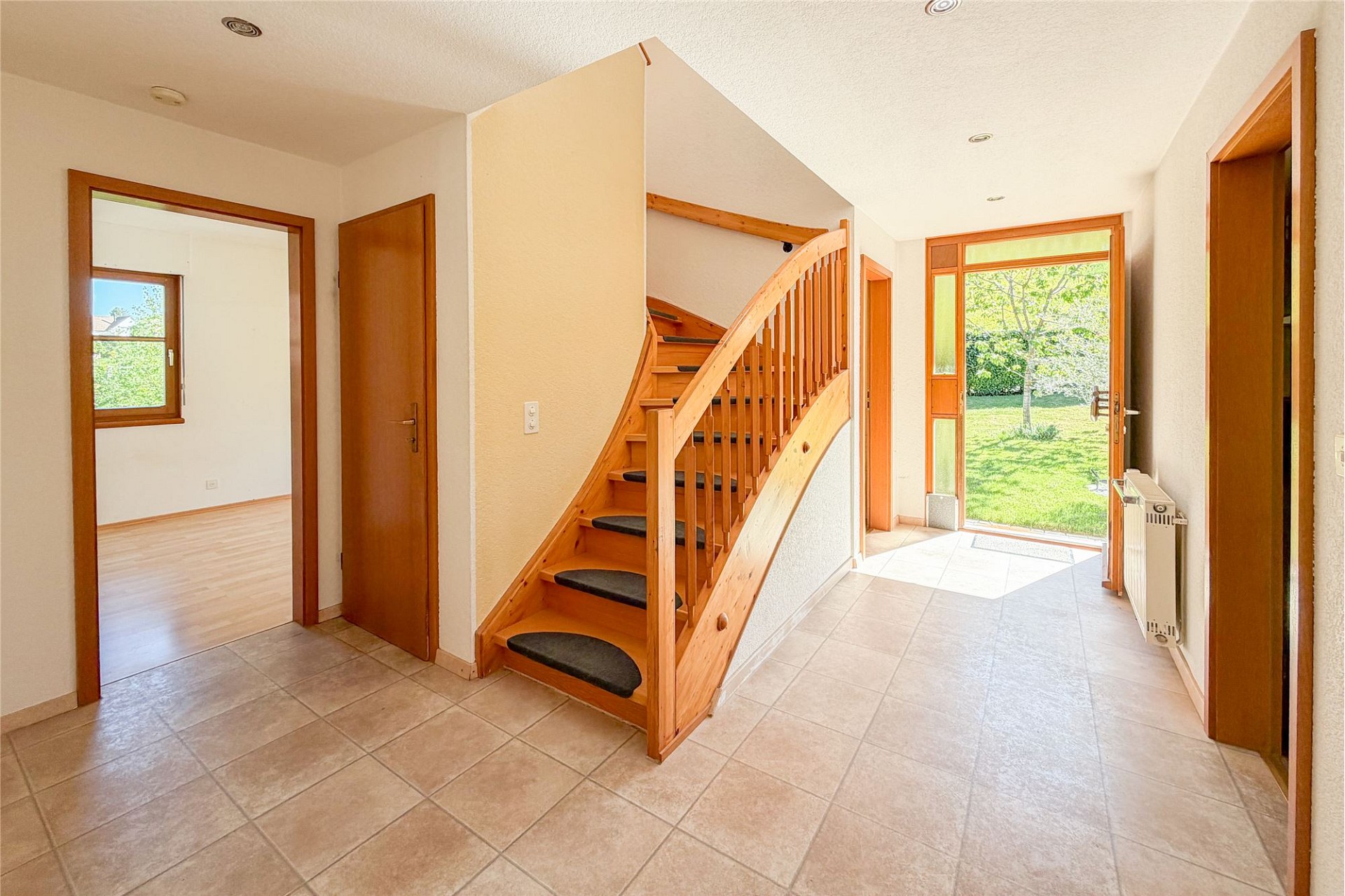 Heller Eingangsbereich mit Holztreppe und Gartenausblick