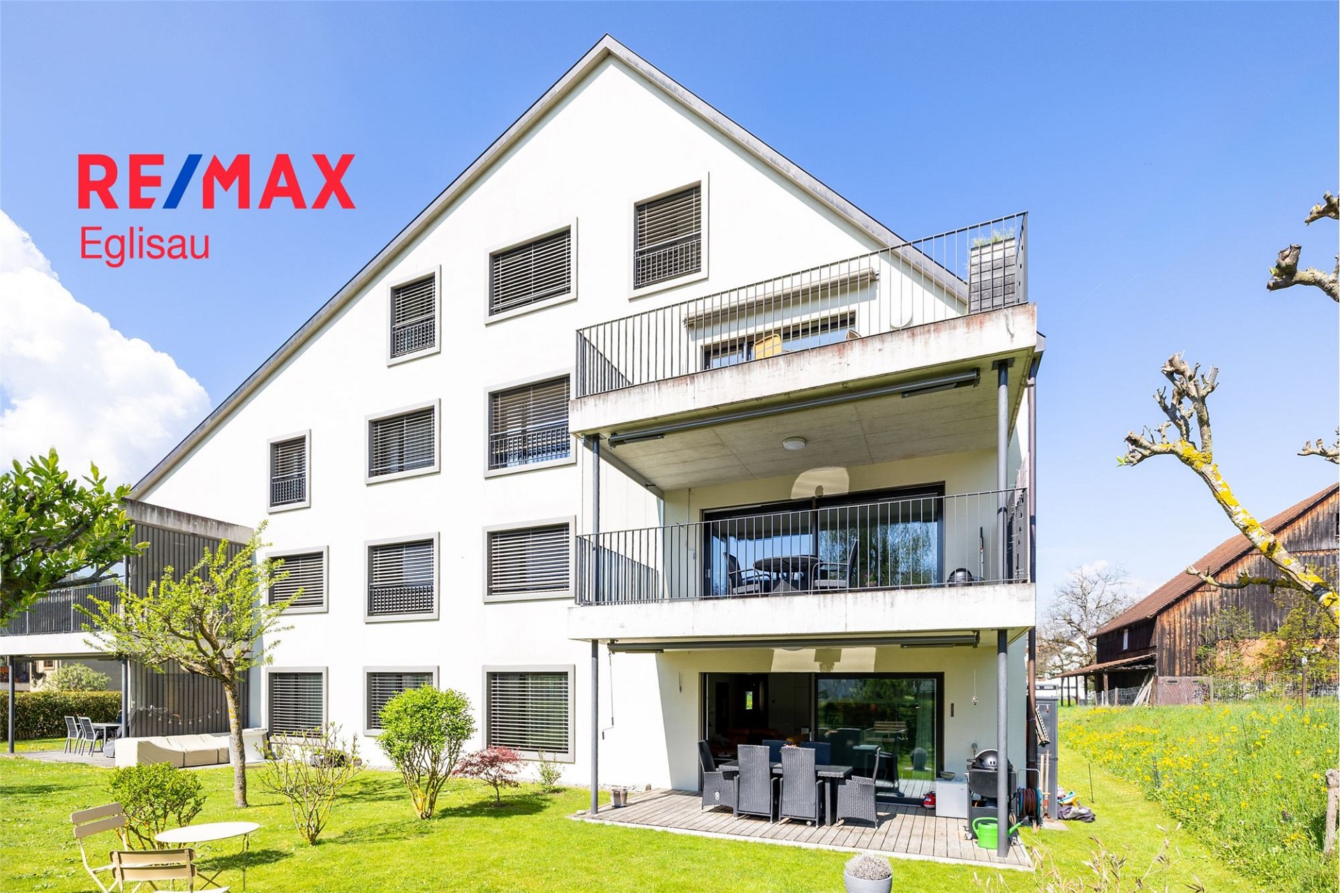 Außenansicht eines modernen Mehrfamilienhauses mit Balkon und Garten