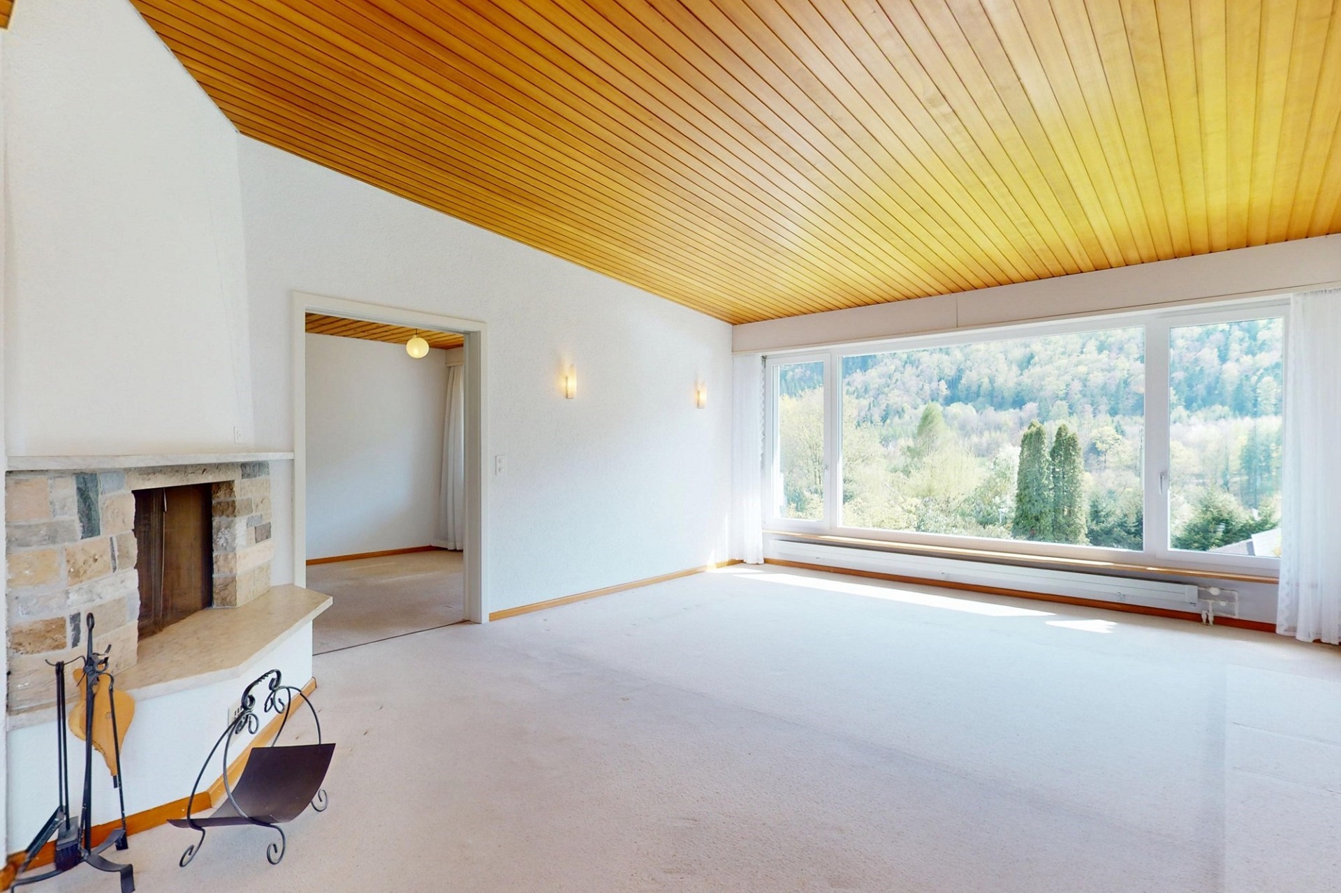 Heller Wohnraum mit großem Panoramafenster und Kamin