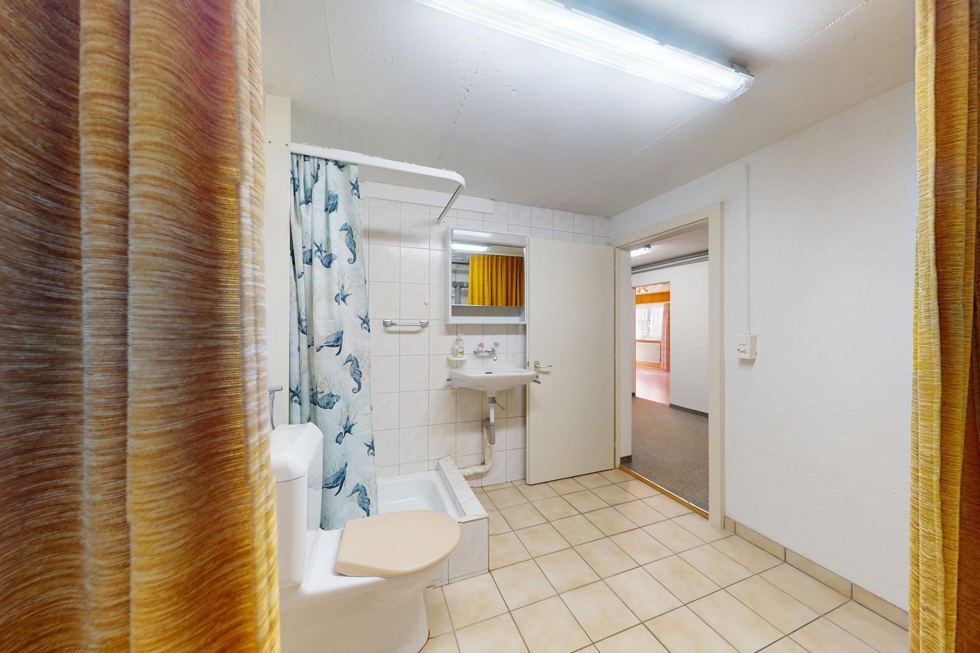 Badezimmer mit Dusche und Blick in den Nebenraum