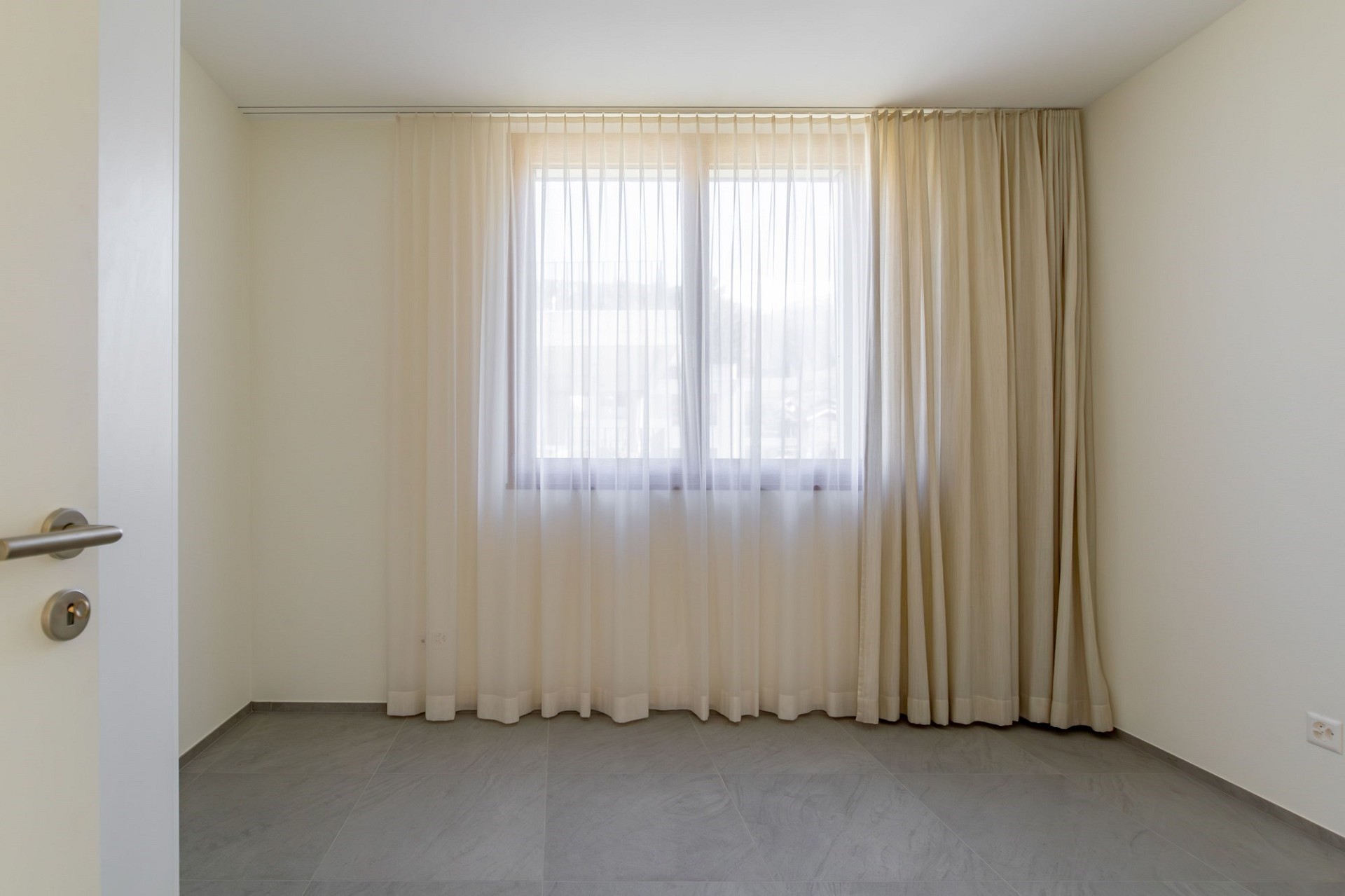 Helles, leeres Zimmer mit Fenster und Vorhängen