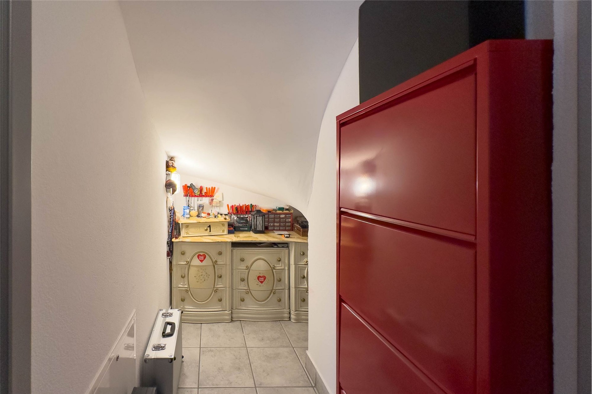 Schmaler Innenraum mit roter Tür und kleinem Schminktisch