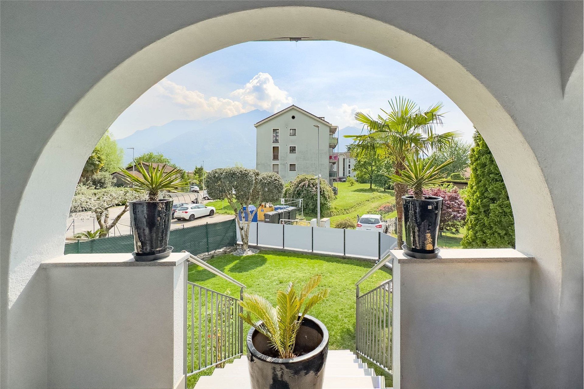 Blick durch einen Rundbogen auf Garten und Berge