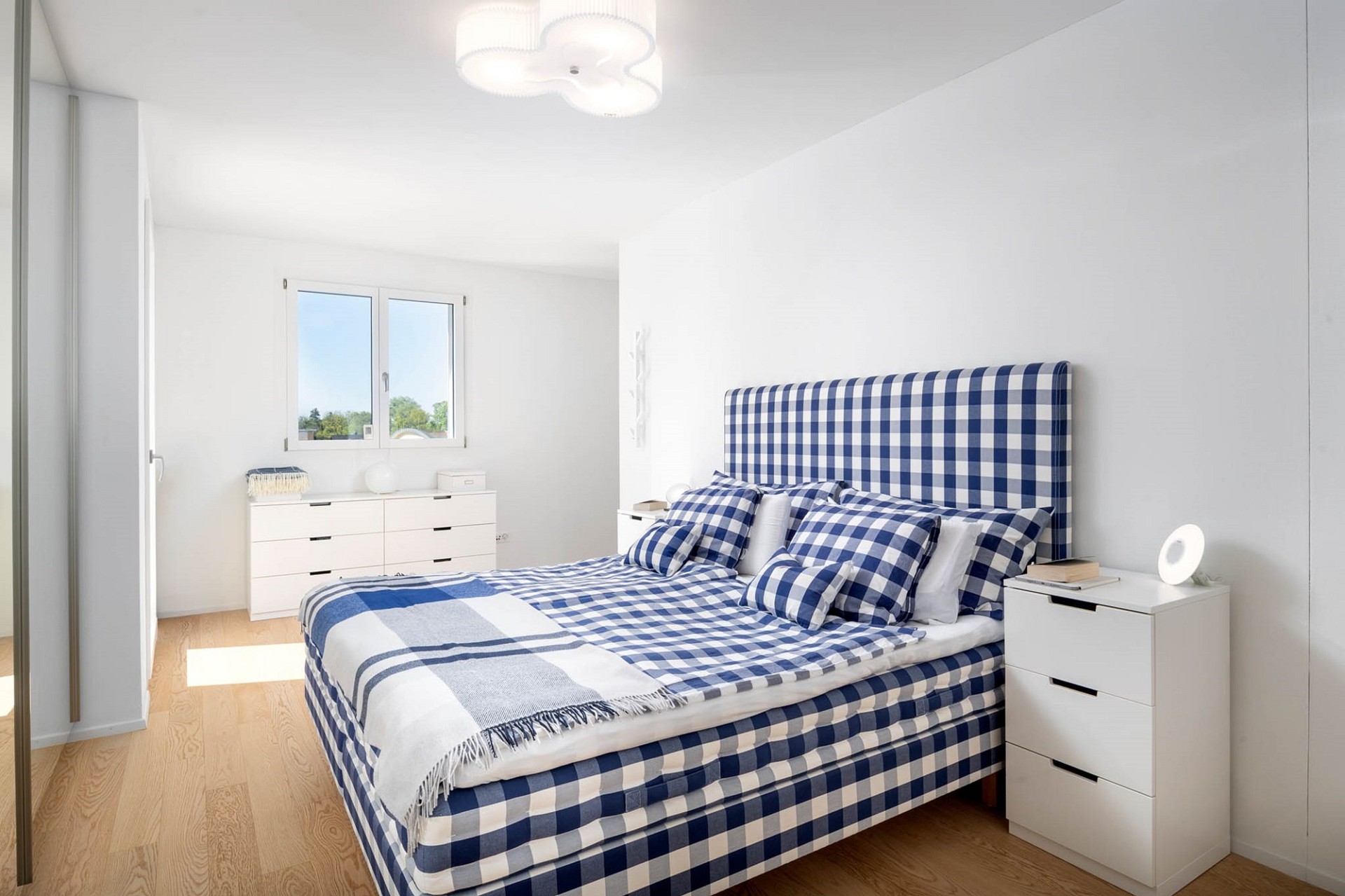 Helles Schlafzimmer mit blau-weiß kariertem Bett