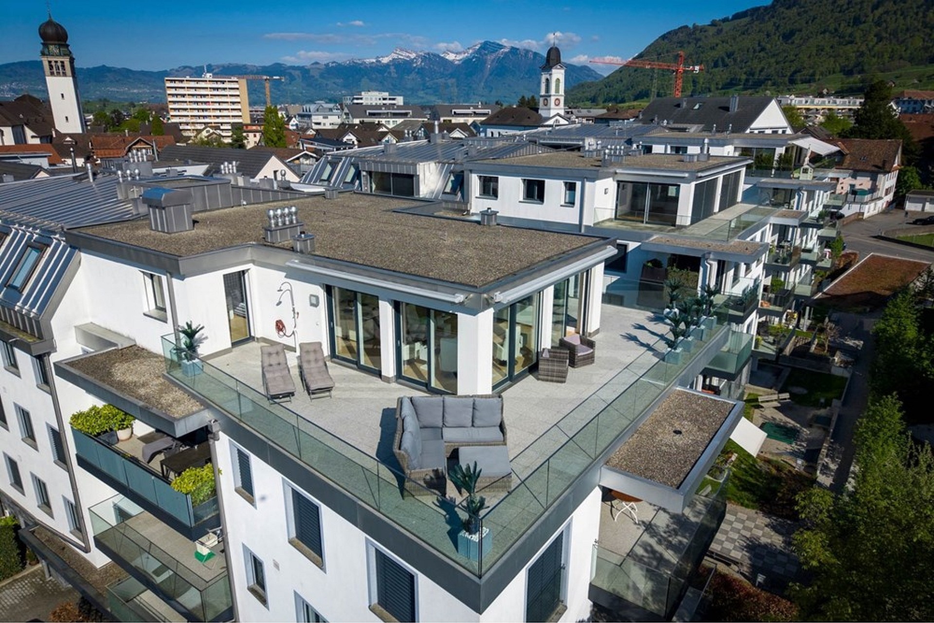 Drohnenaufnahme eines modernen Wohngebäudes mit Dachterrasse und Alpenblick