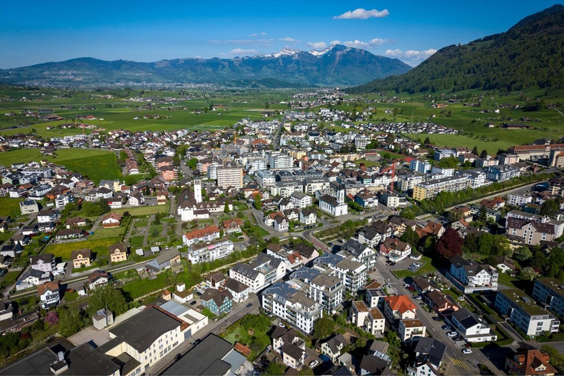 Luftaufnahme einer Stadt in einer alpinen Tallandschaft