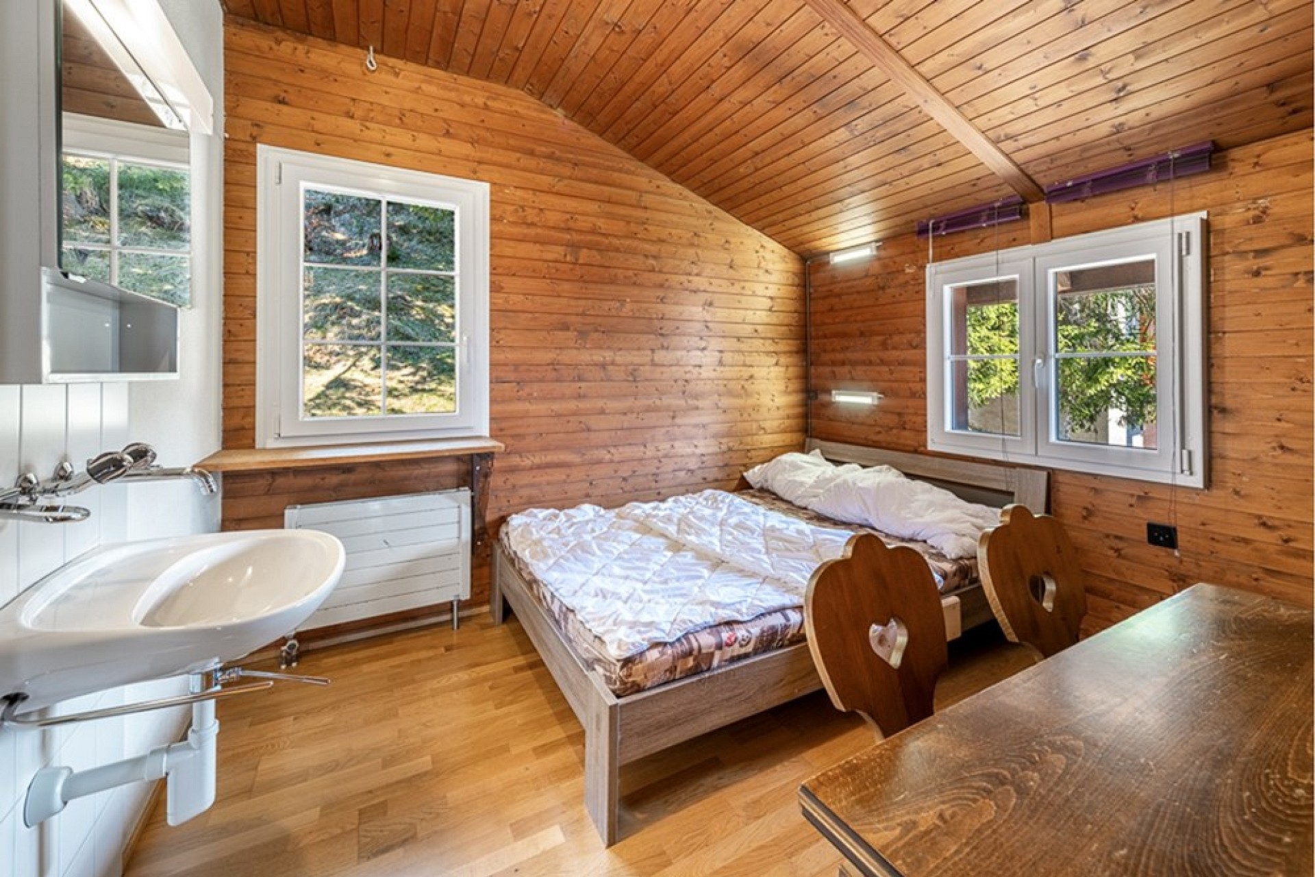 Gemütliches Holzzimmer mit Bett und Waschbecken
