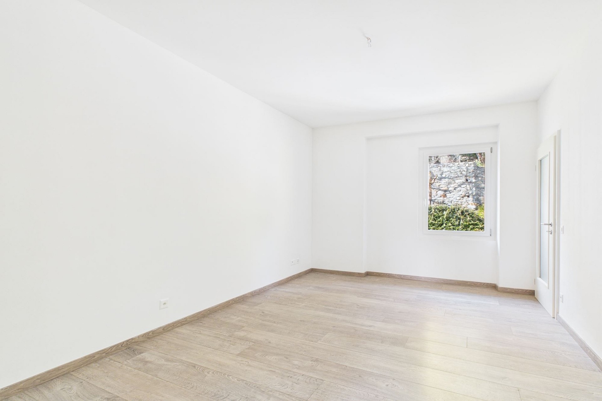 Helles, leeres Zimmer mit Holzoptikboden