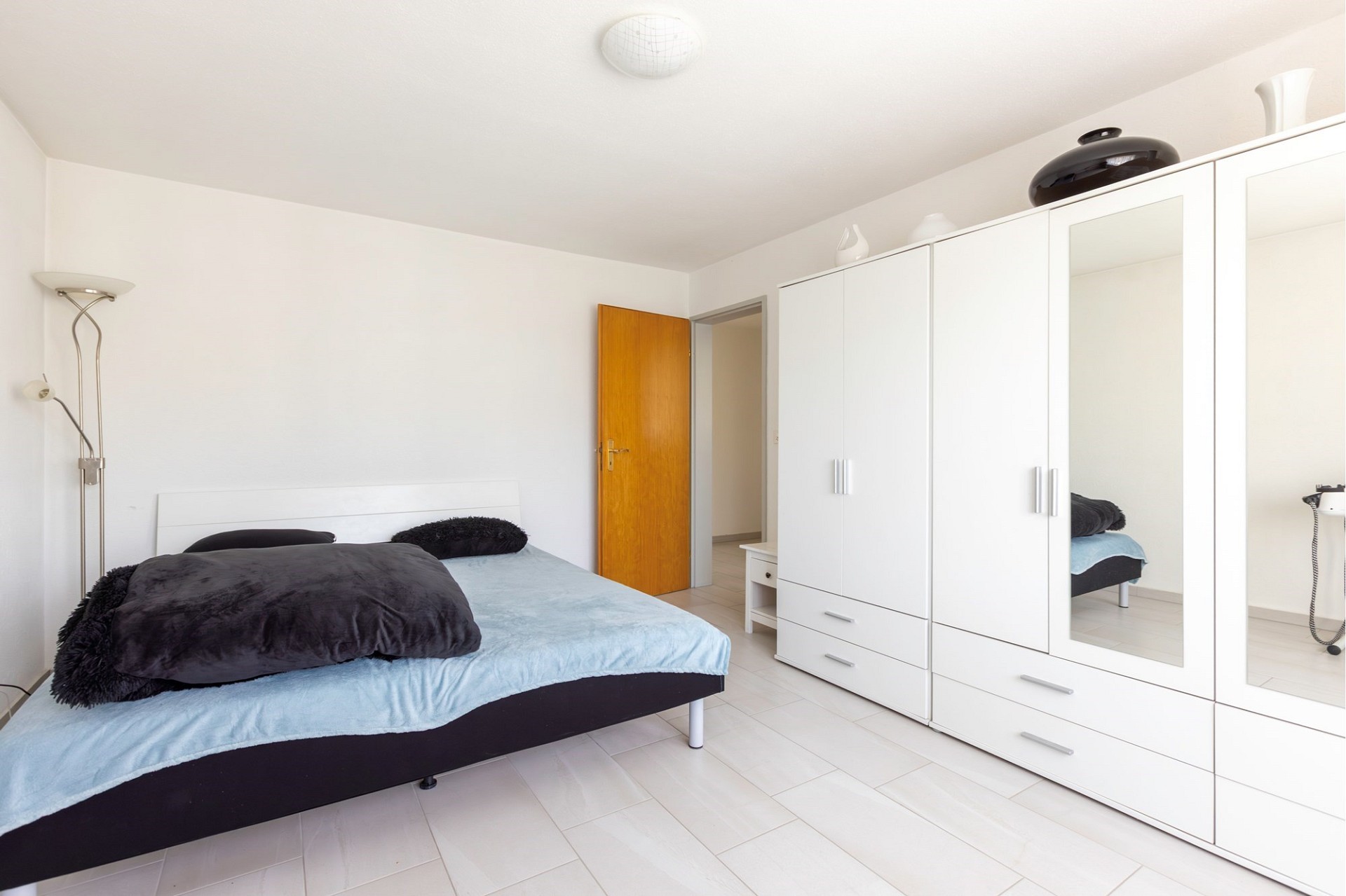 Helles Schlafzimmer mit weißem Kleiderschrank und Doppelbett