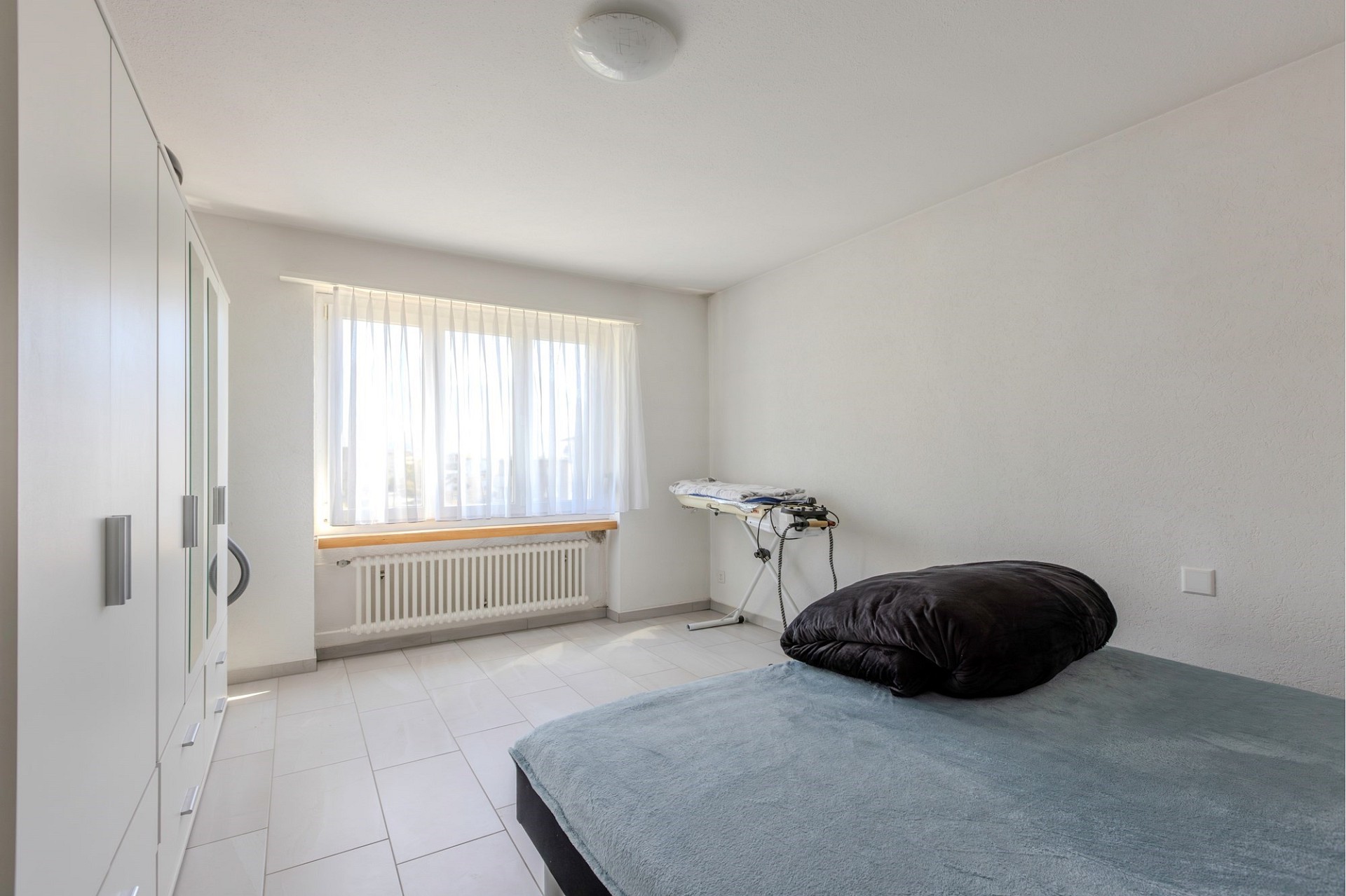 Helles Schlafzimmer mit Schrankwand und Fenster