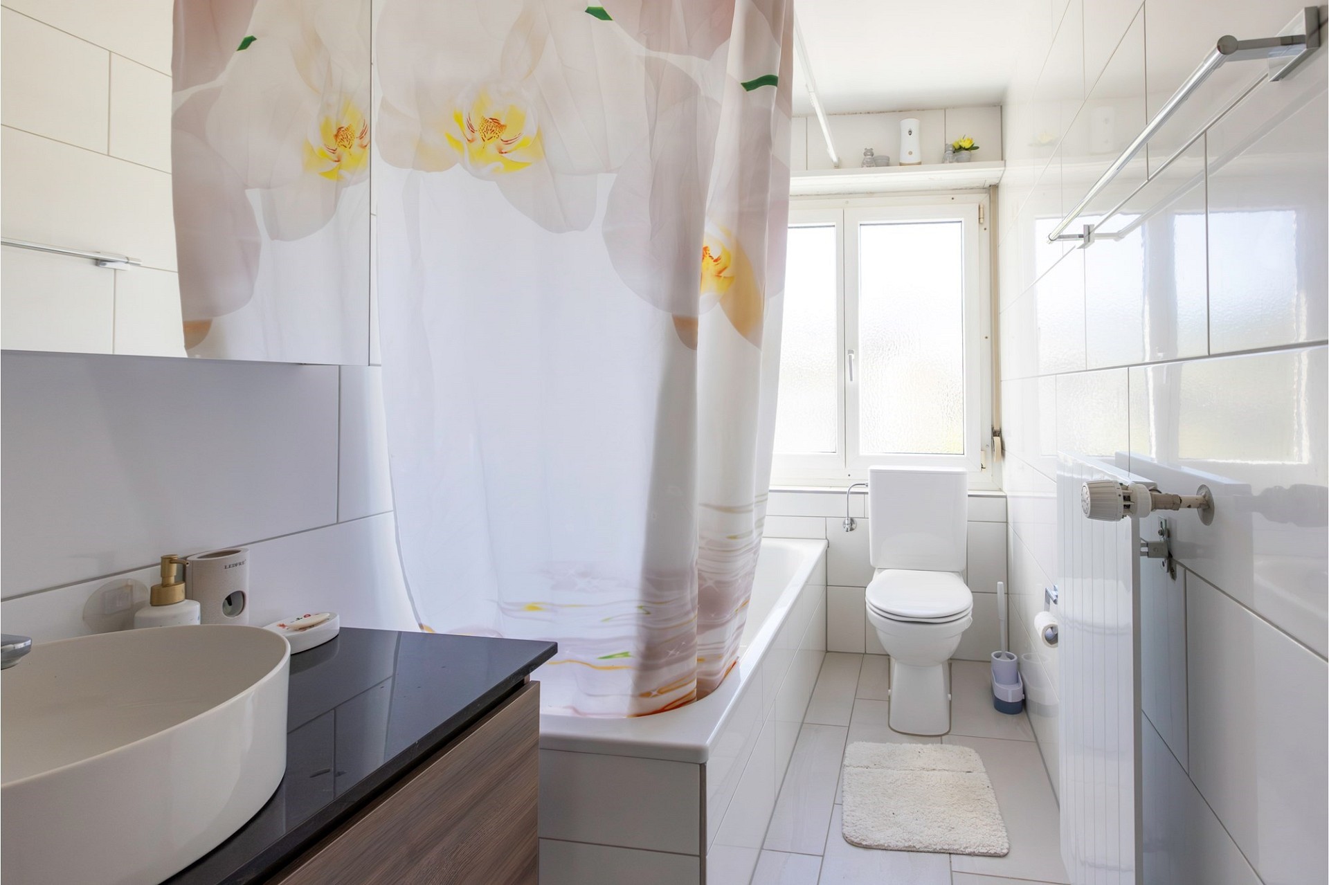 Helles, schmales Badezimmer mit Badewanne, WC und Waschtisch