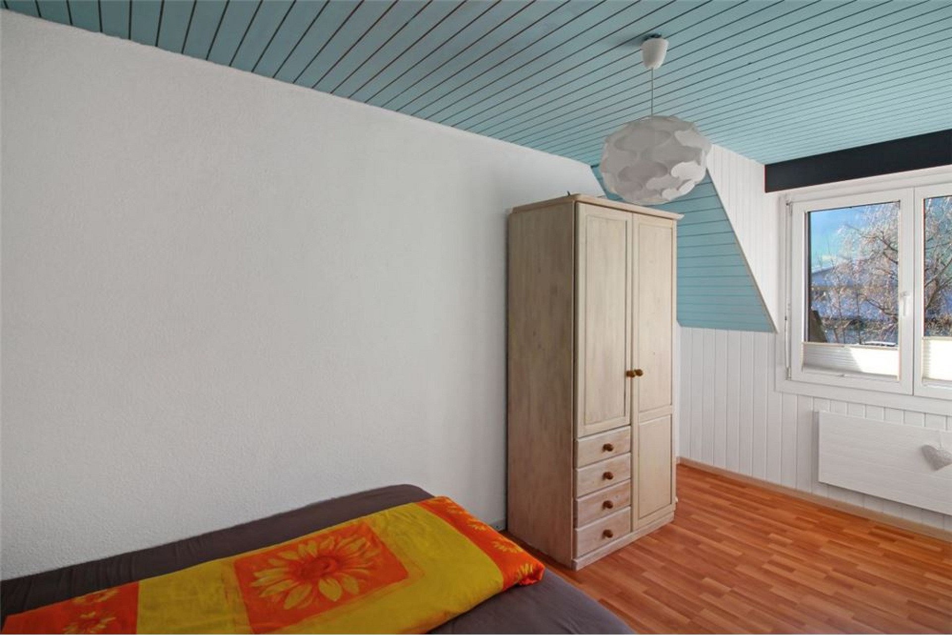 Dachzimmer mit Einzelbett und Kleiderschrank