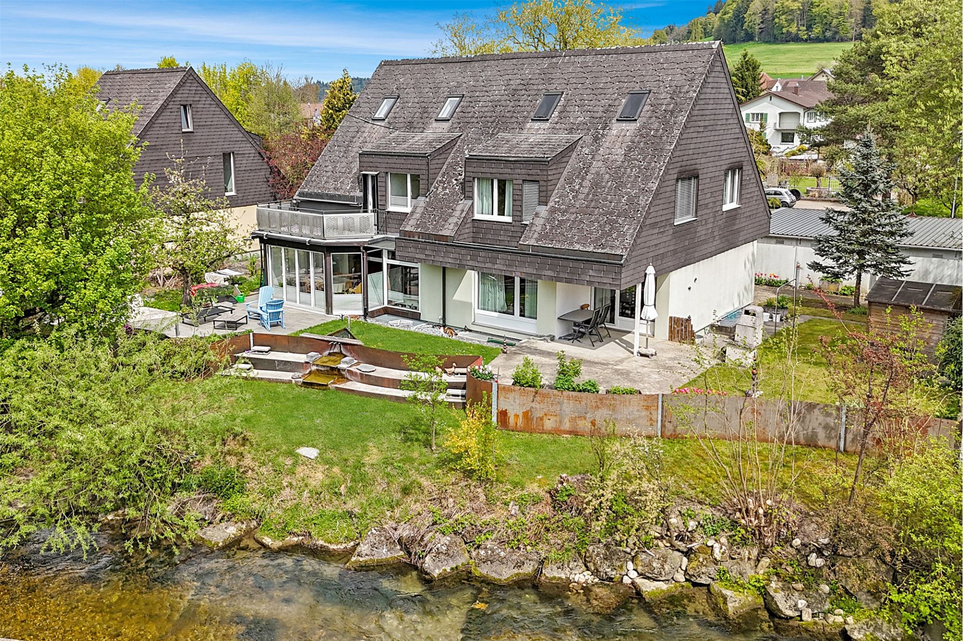 Außenansicht eines Hauses am Wasser mit Garten und Terrasse