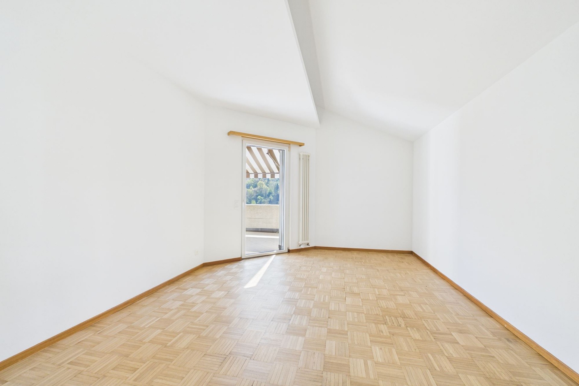 Leerer heller Raum mit Parkett und Balkonzugang
