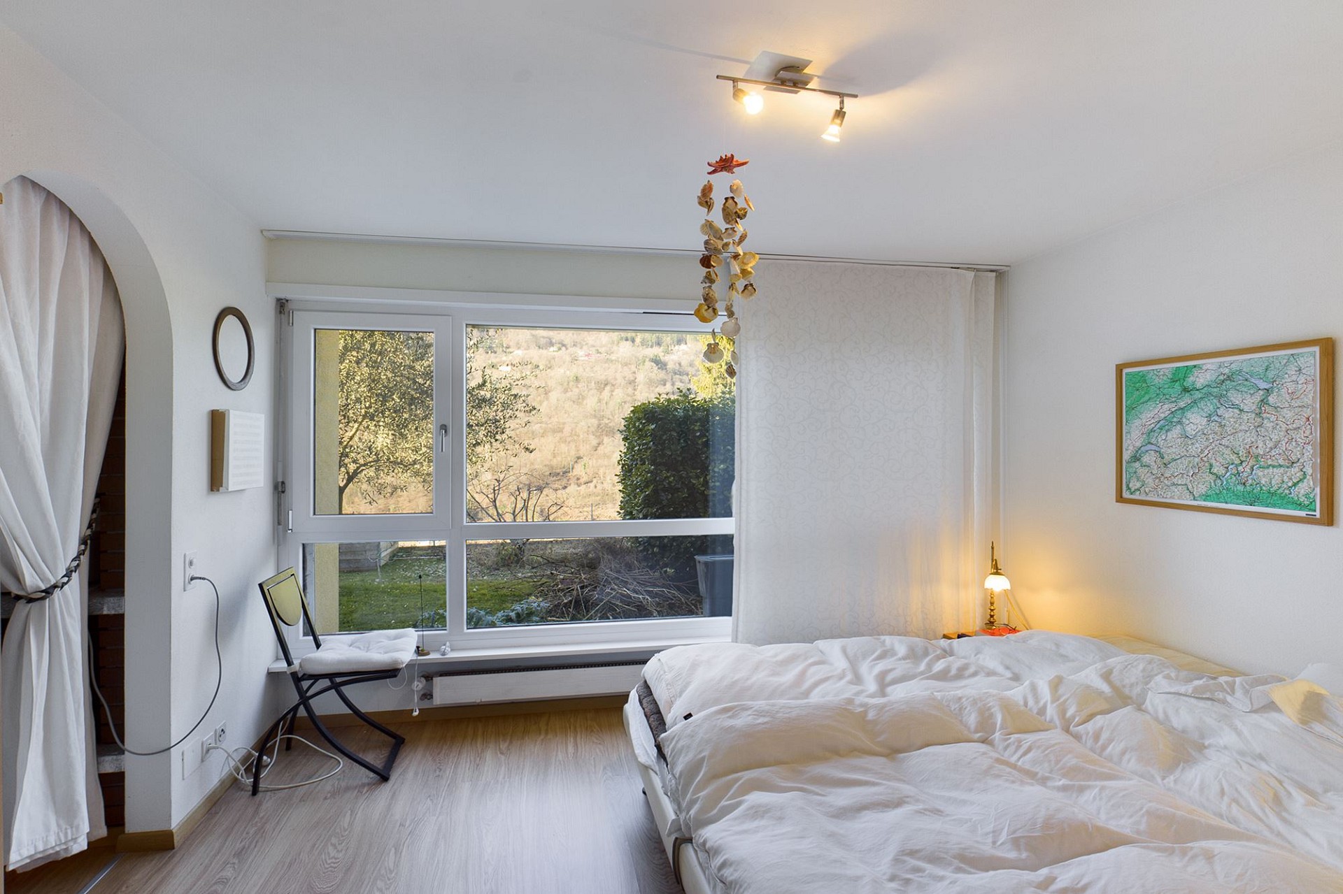 Helles Schlafzimmer mit großem Fenster und Blick ins Grüne