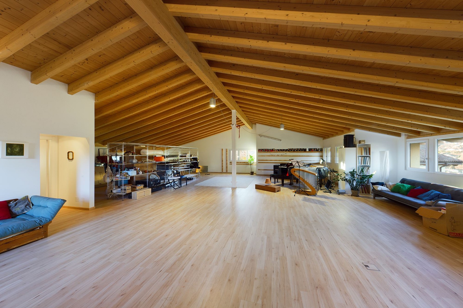 Großer offener Wohnraum mit sichtbarer Holzdecke