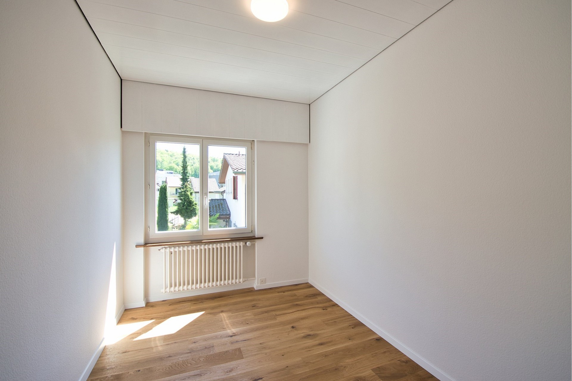 Helles, leeres Zimmer mit Fenster und Heizkörper