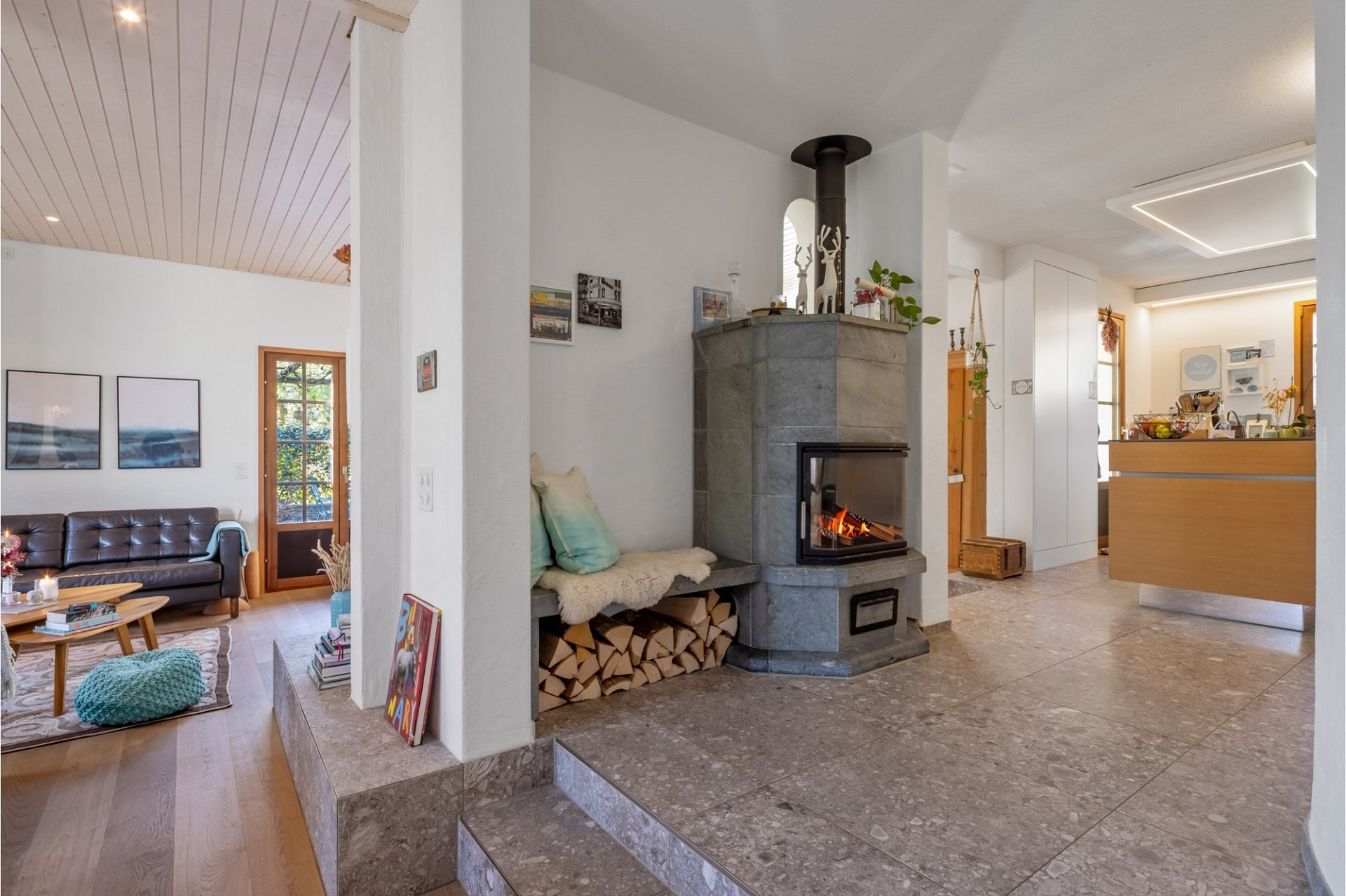 Offener Wohnbereich mit Kamin und angrenzendem Küchenbereich