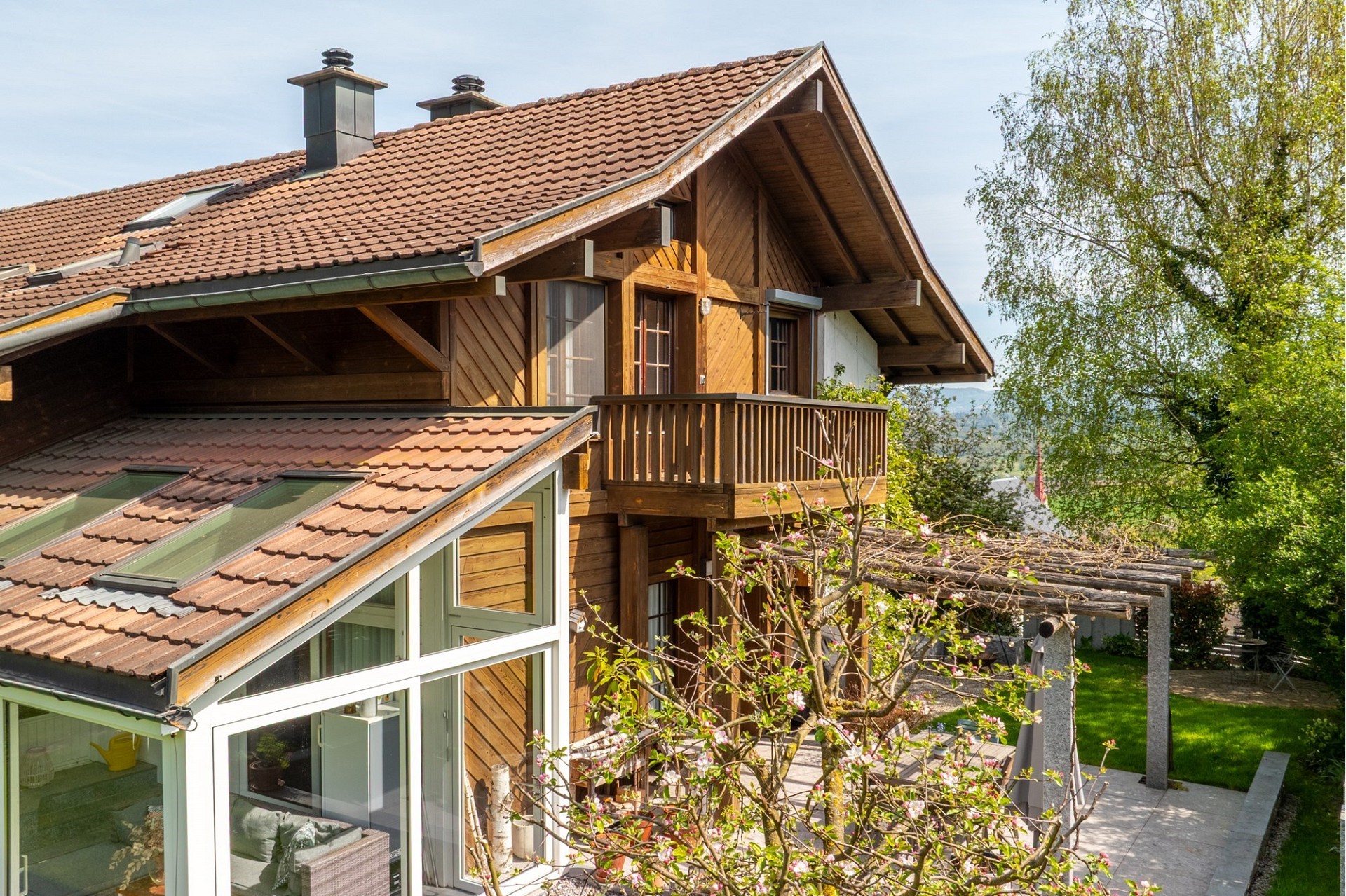 Außenansicht eines Holzhauses mit Balkon und Garten