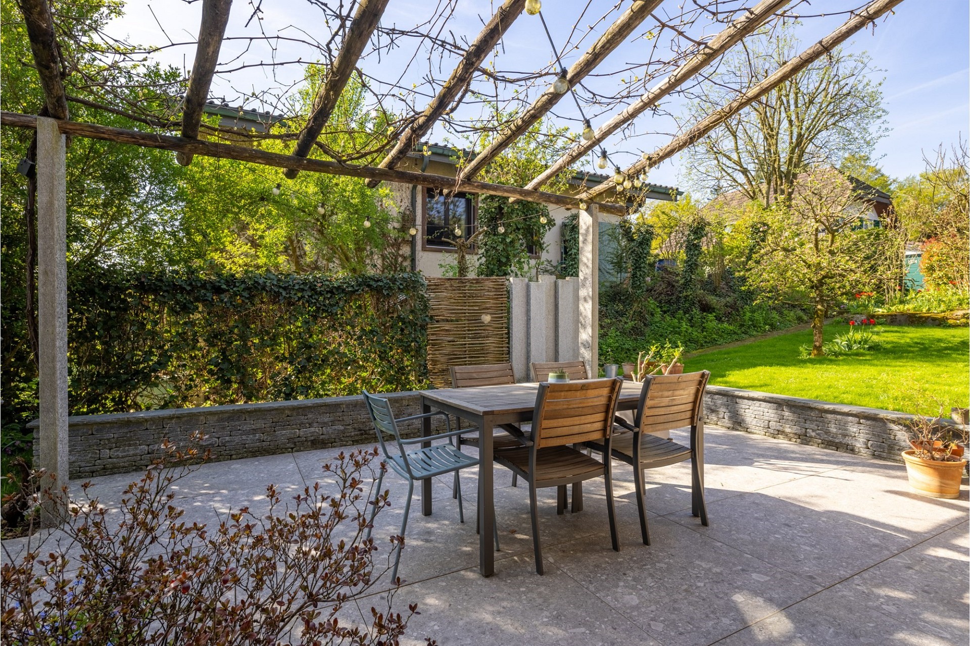 Gepflasterte Garten-Terrasse mit Pergola und Essgruppe