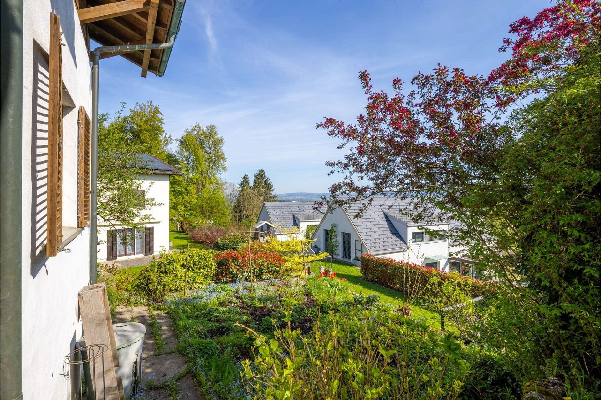 Heller Gartenblick mit Wohnhäusern und Blick ins Grüne