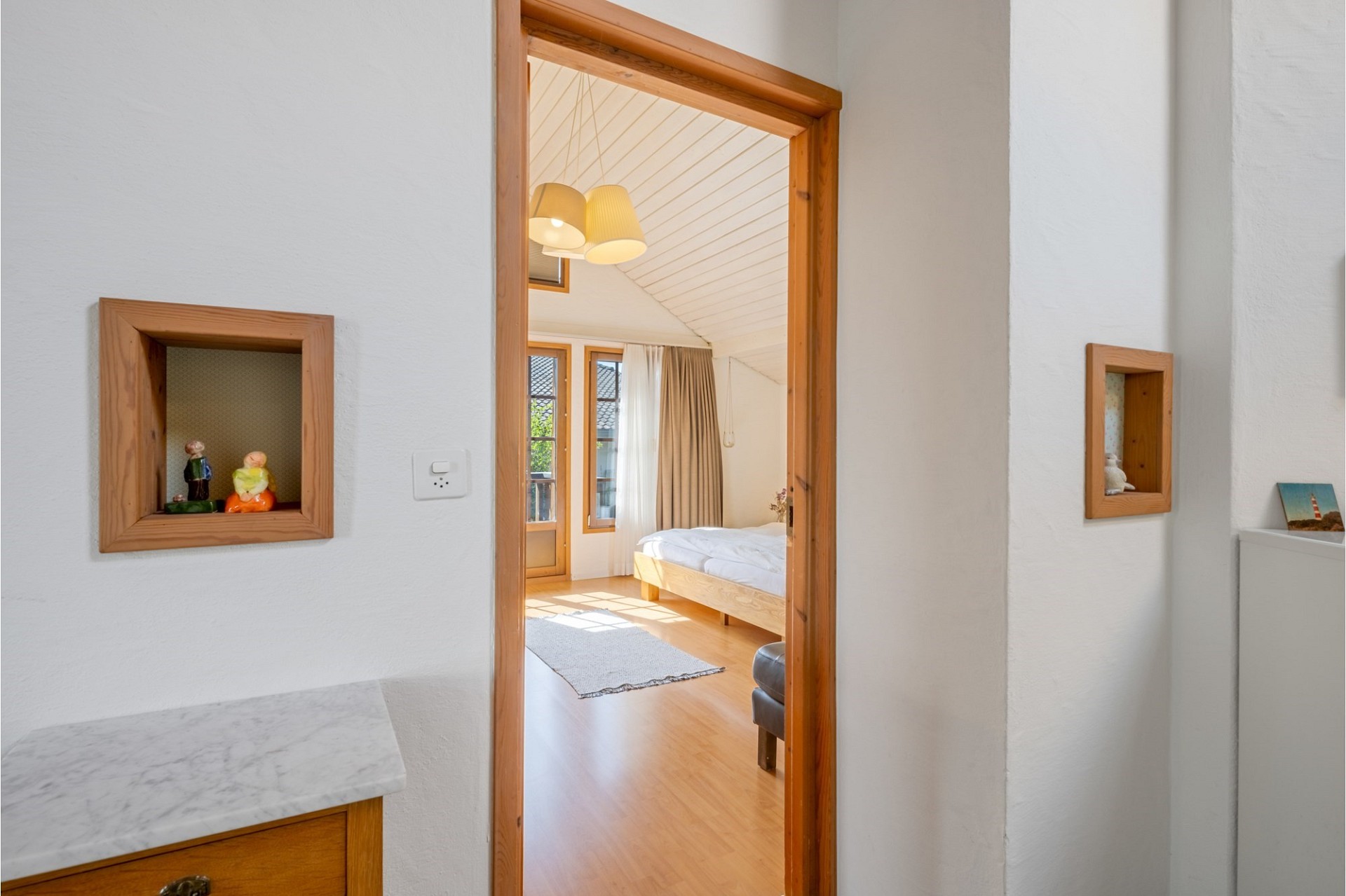 Heller Blick durch eine Türöffnung ins Schlafzimmer