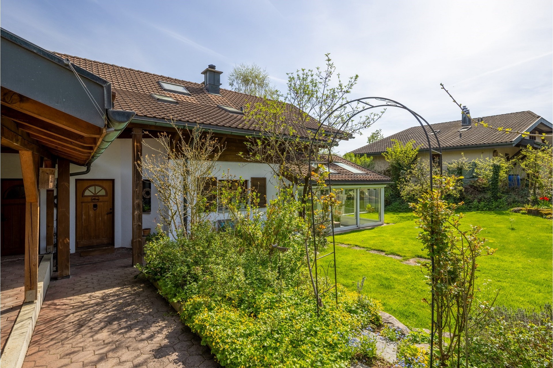 Gartenansicht eines Wohnhauses mit Terrasse und Wintergarten