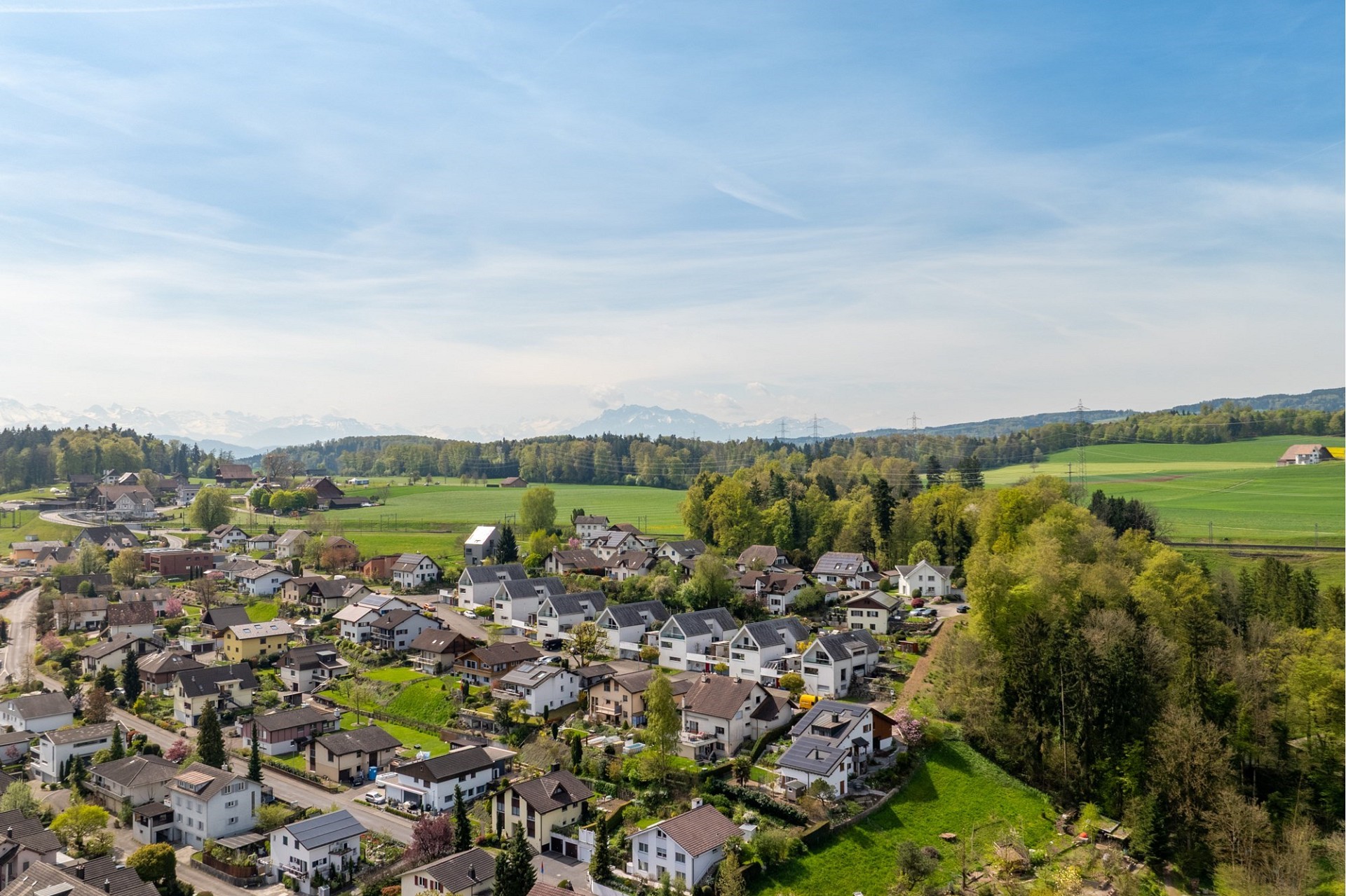 Luftaufnahme eines Wohngebiets mit Alpenpanorama