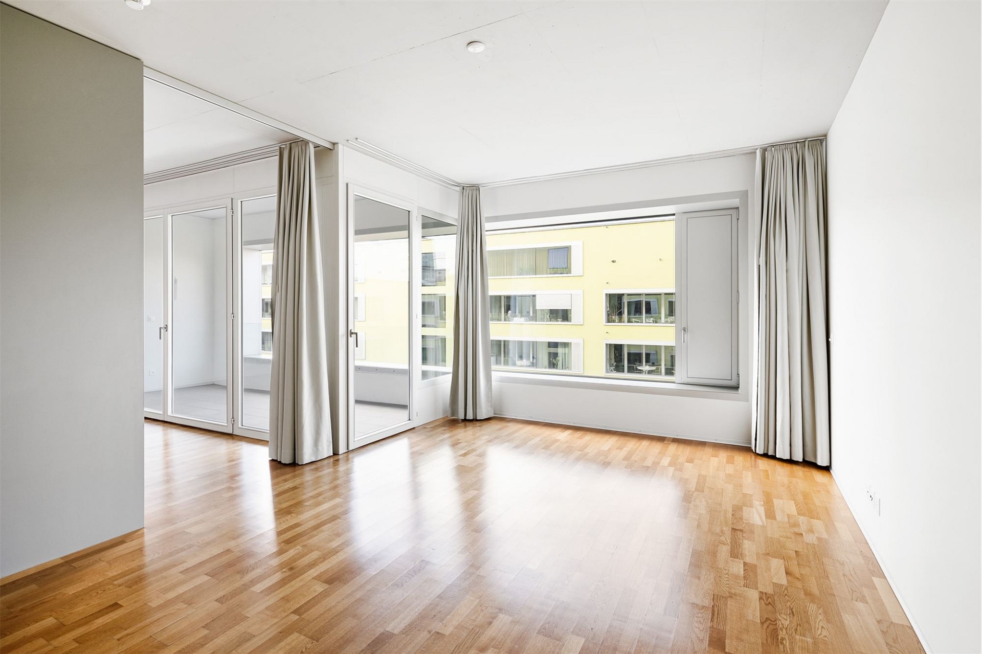 Helles Wohn-/Schlafzimmer mit Parkett und großen Fenstern
