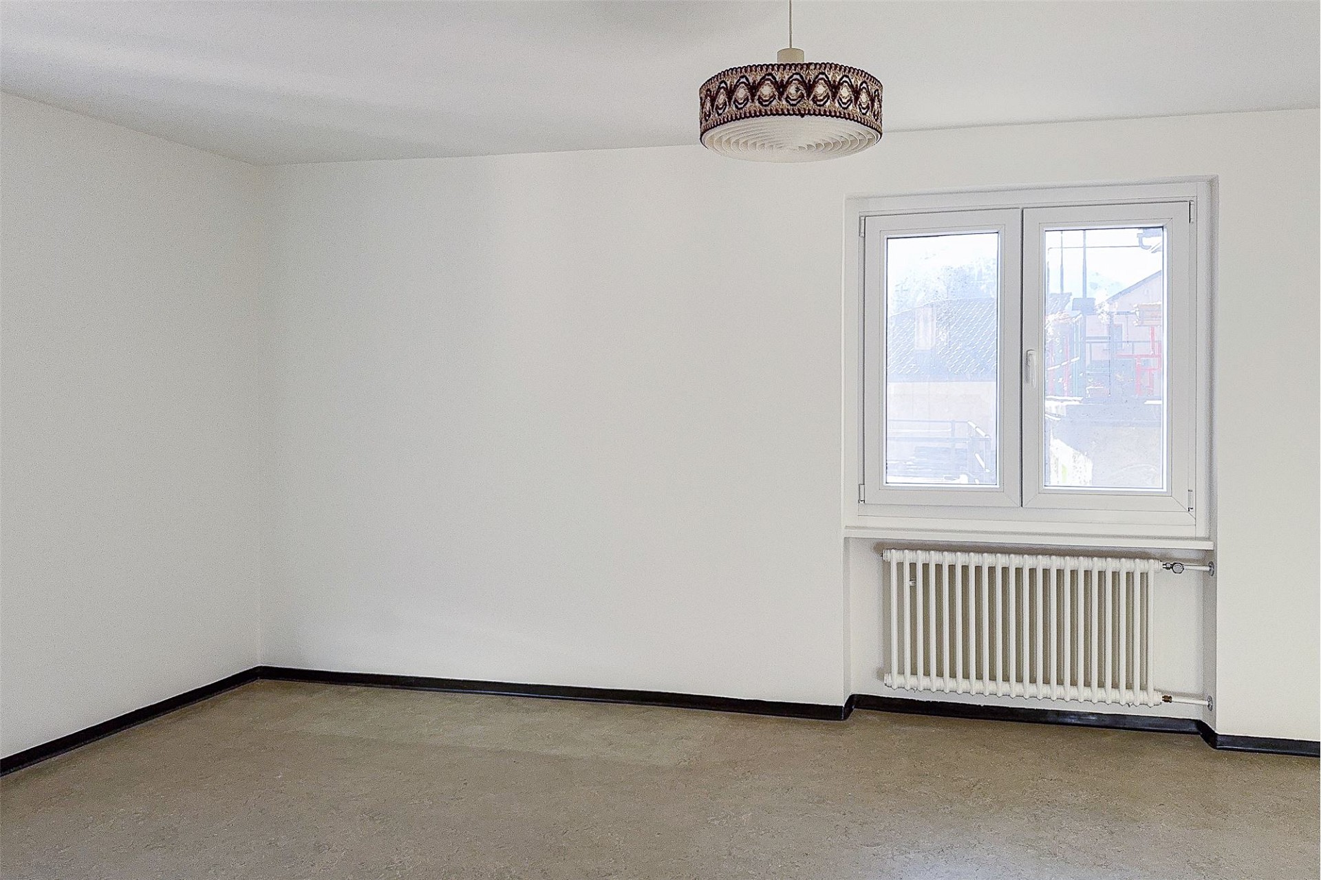 Leerer, heller Raum mit Fenster und Heizkörper