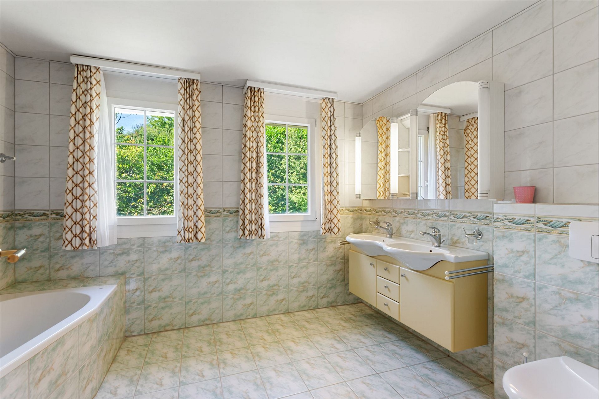 Helles Badezimmer mit Badewanne, Doppelwaschtisch und Fenstern