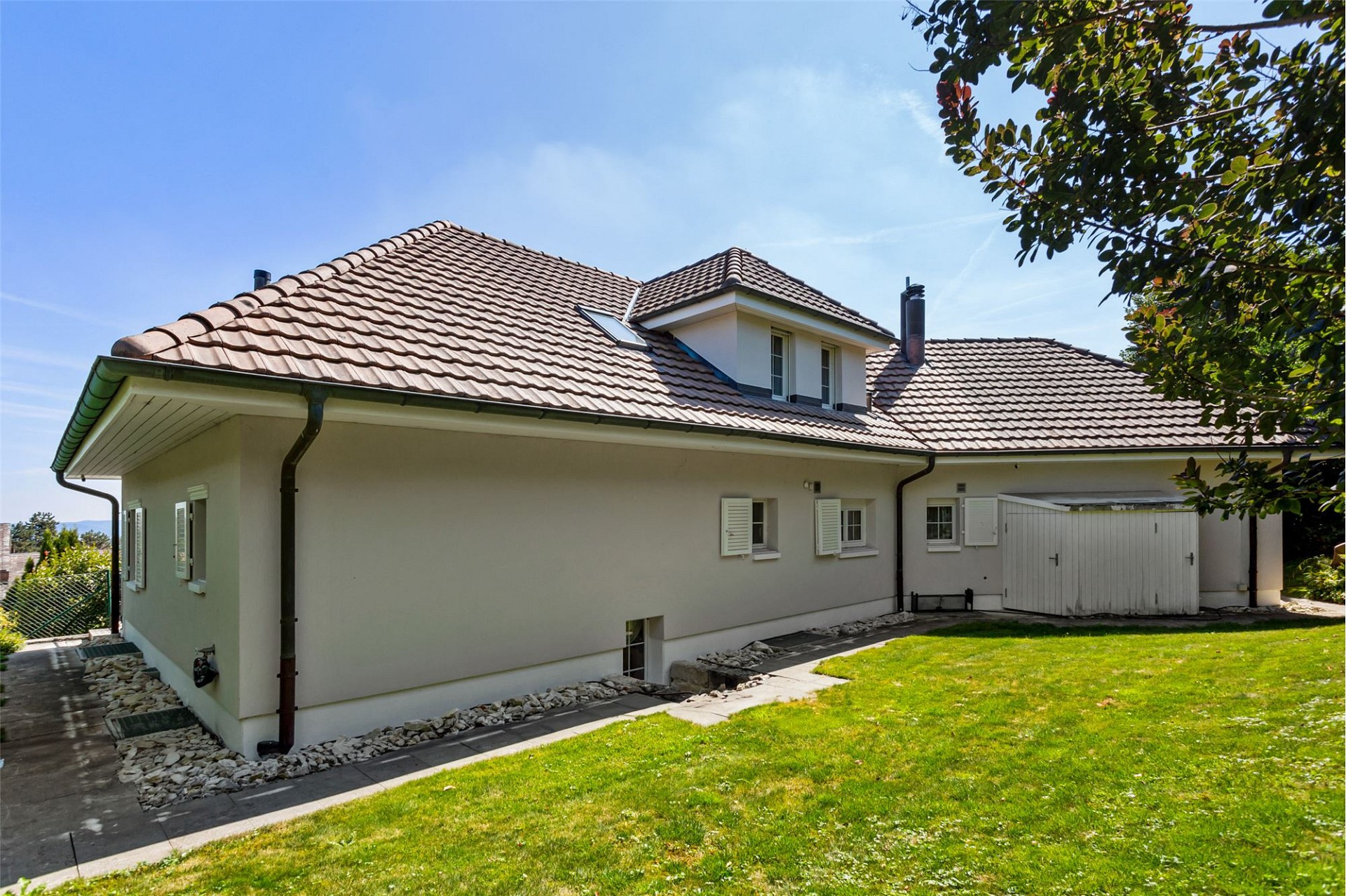 Einfamilienhaus mit Ziegeldach und Gartenansicht