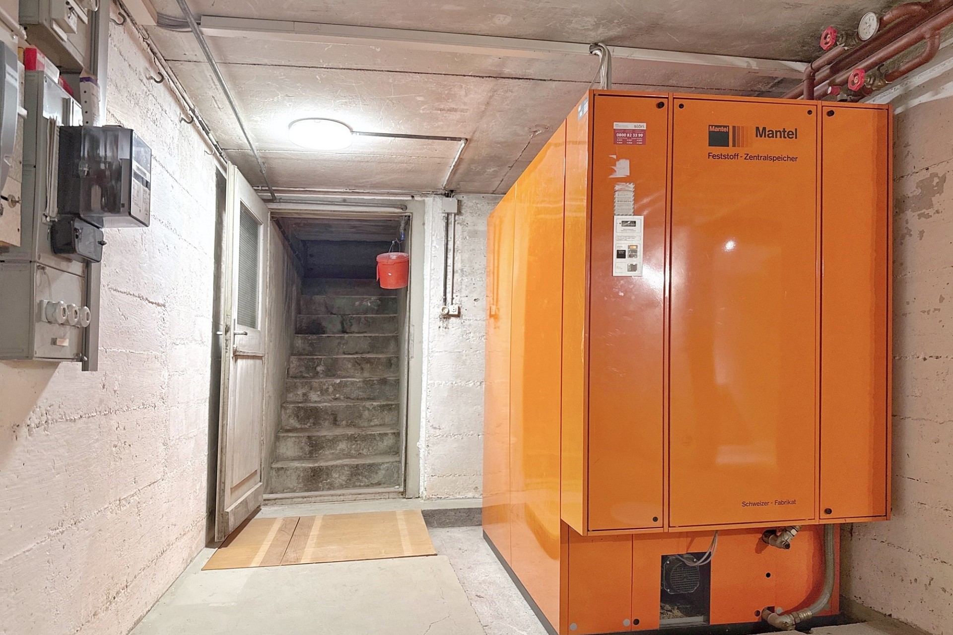 Heizraum im Keller mit großem orangefarbenem Zentral­speicher