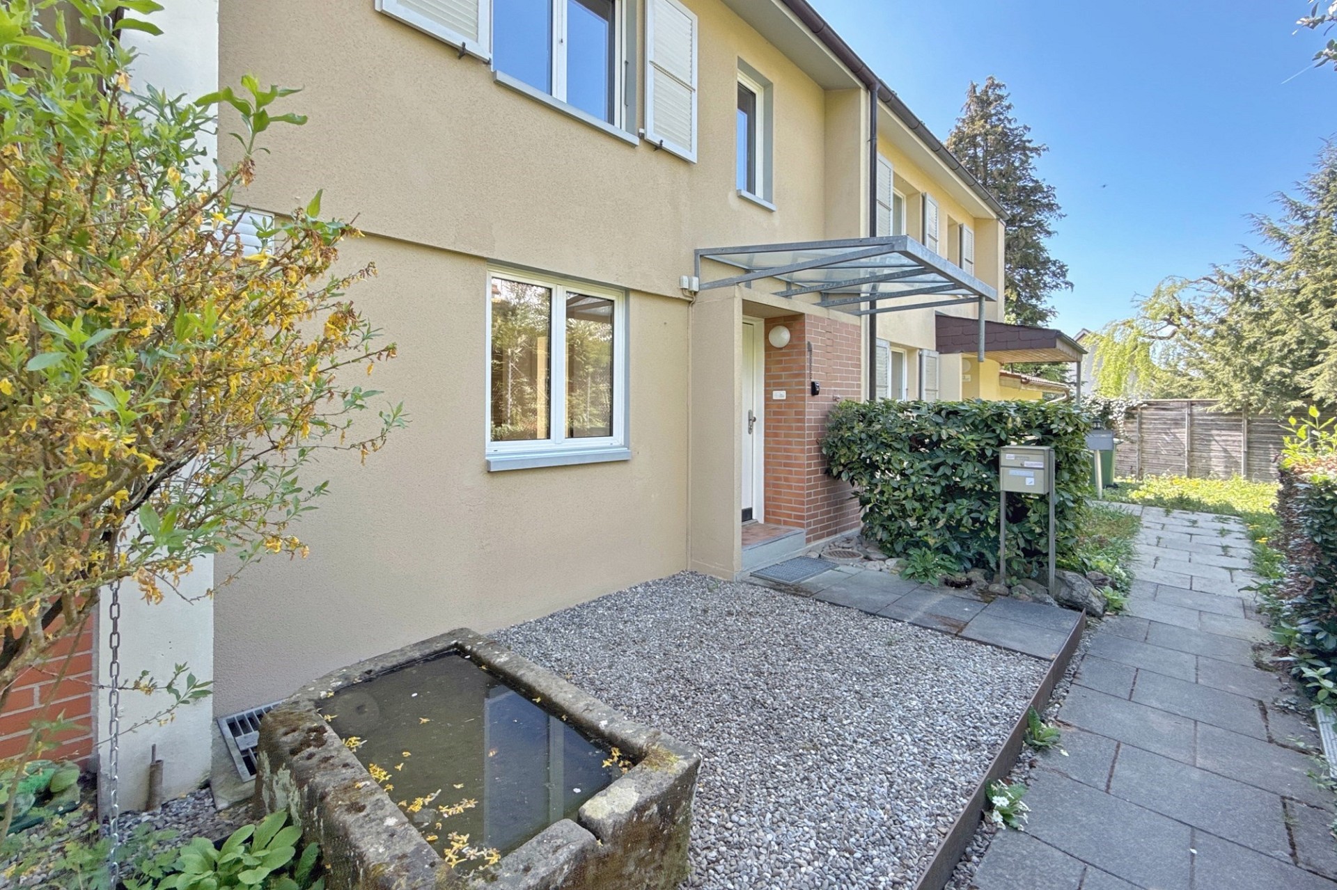 Außenansicht eines Reihen- oder Doppelhauses mit Hauseingang und Gartenweg