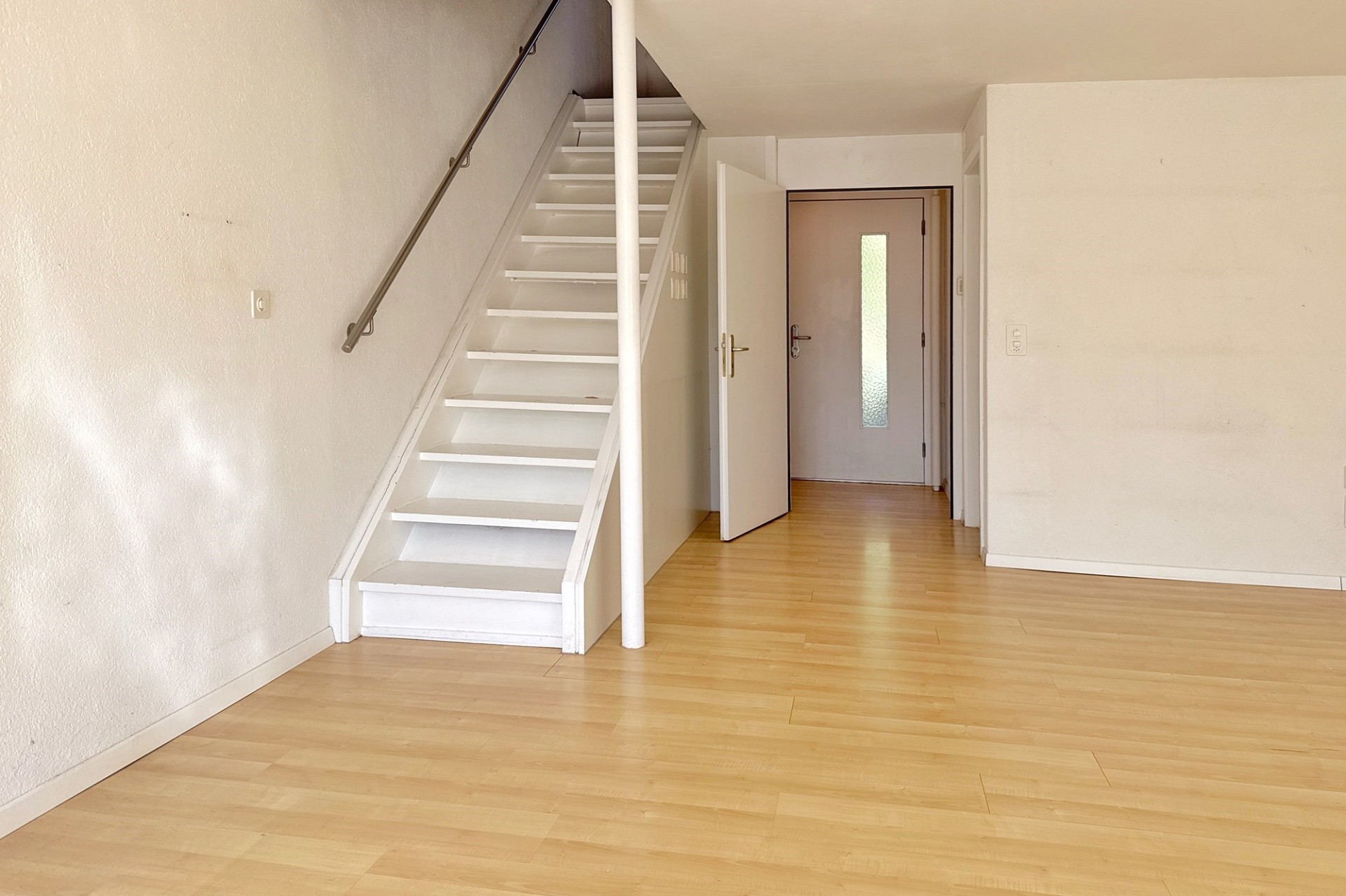 Heller Wohnraum mit Treppe und Eingangstür