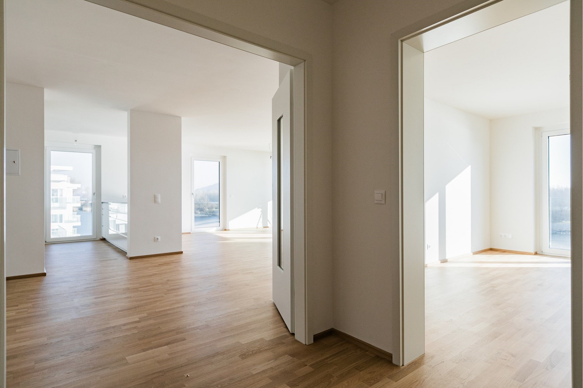 Helle, leere Wohnung mit Holzfußboden und mehreren Durchgängen