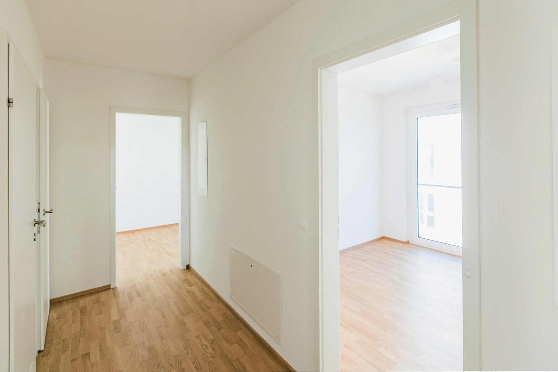 Heller Flur mit Holzfußboden und angrenzenden Räumen