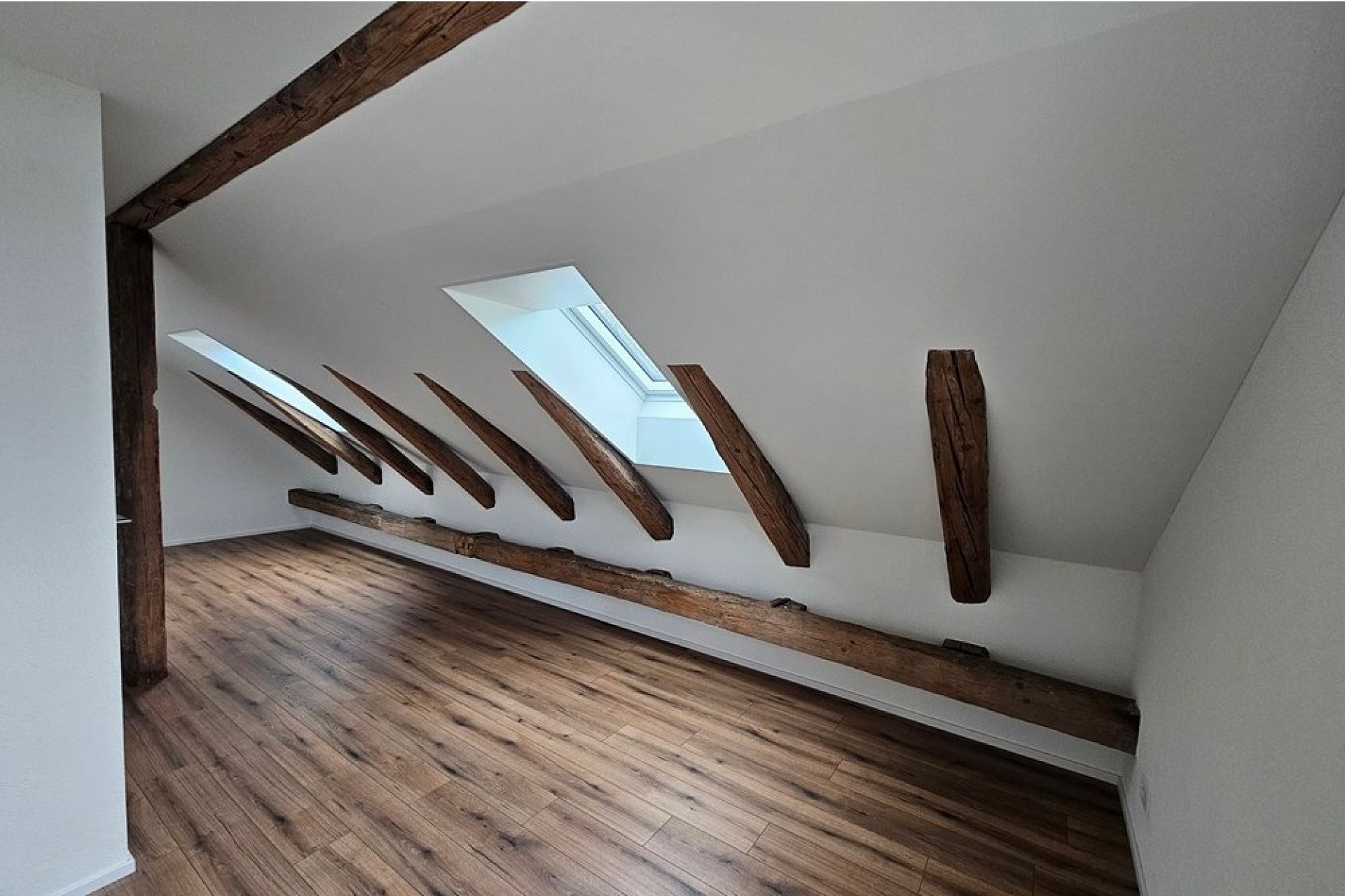 Dachgeschossraum mit Dachfenstern und sichtbaren Holzbalken
