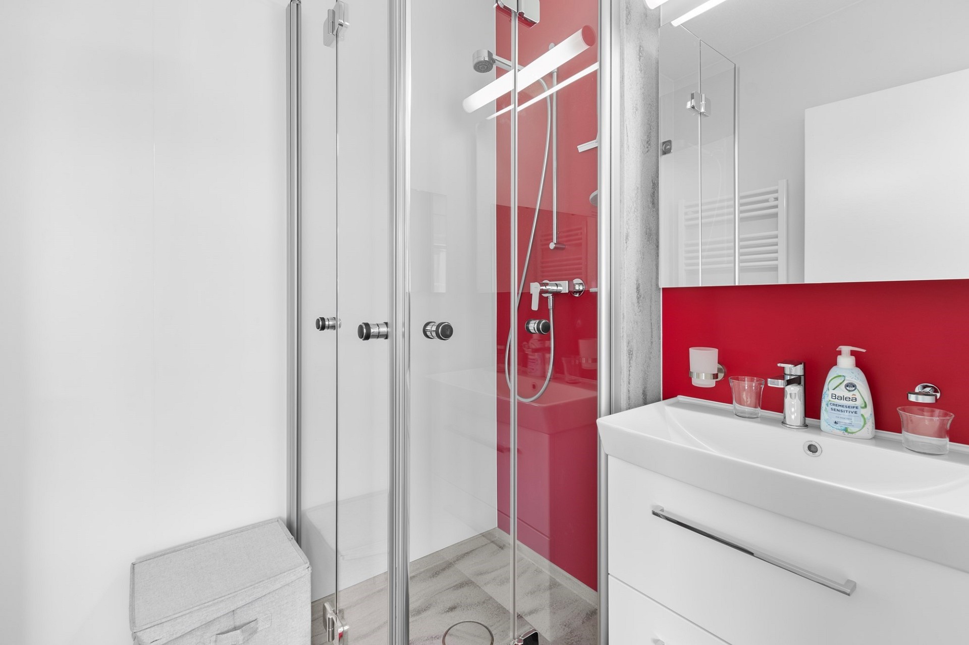 Modernes Badezimmer mit Glasdusche und roter Akzentwand