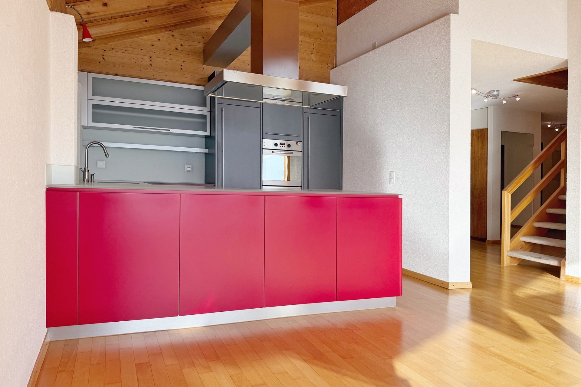 Moderne Küche mit roter Front und Holzdecke