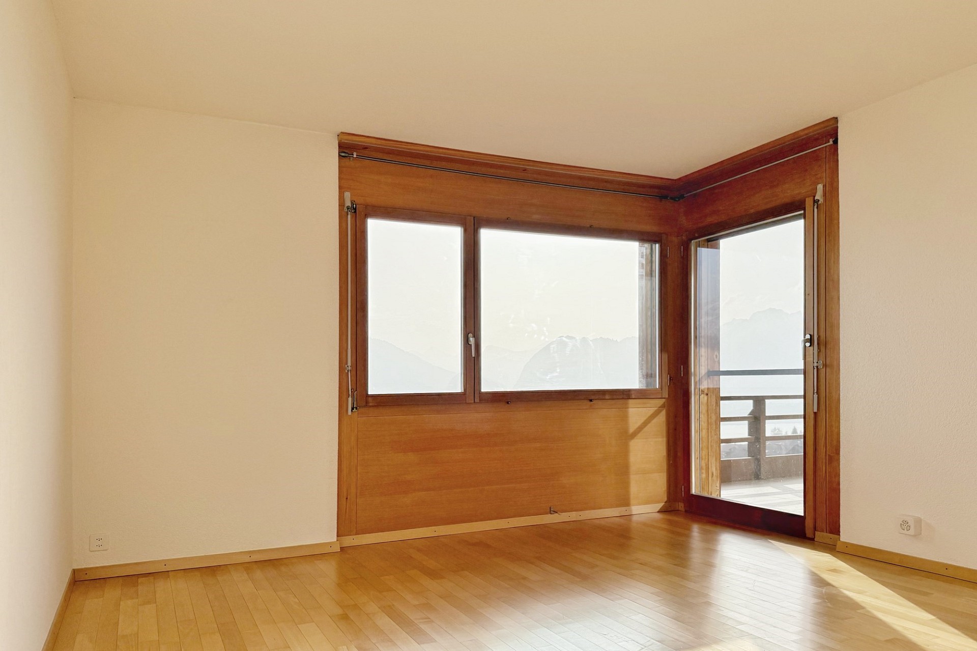 Heller leerer Raum mit Holzfenster und Balkonblick