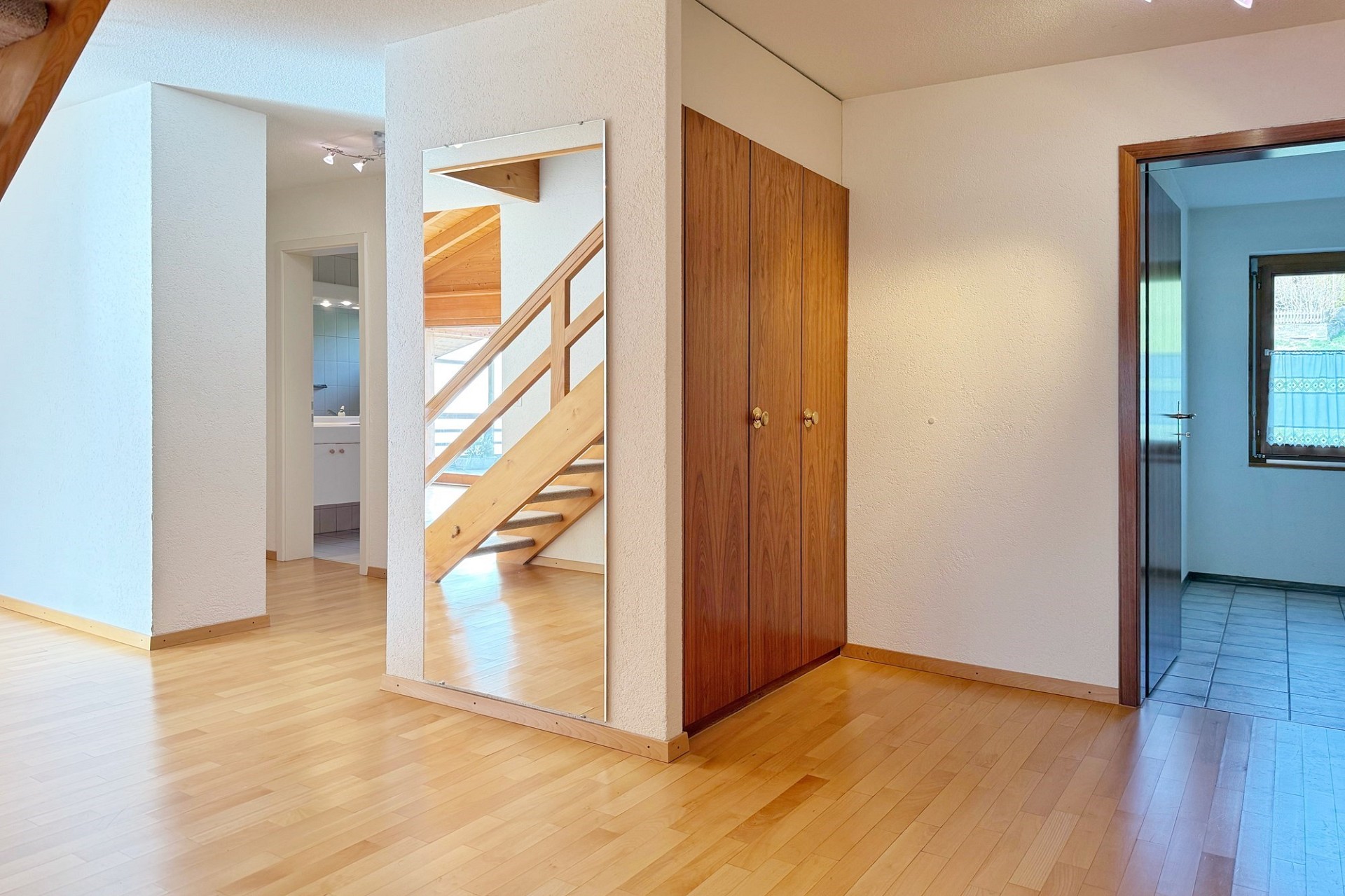 Heller Flur mit Holztreppe und Einbauschrank