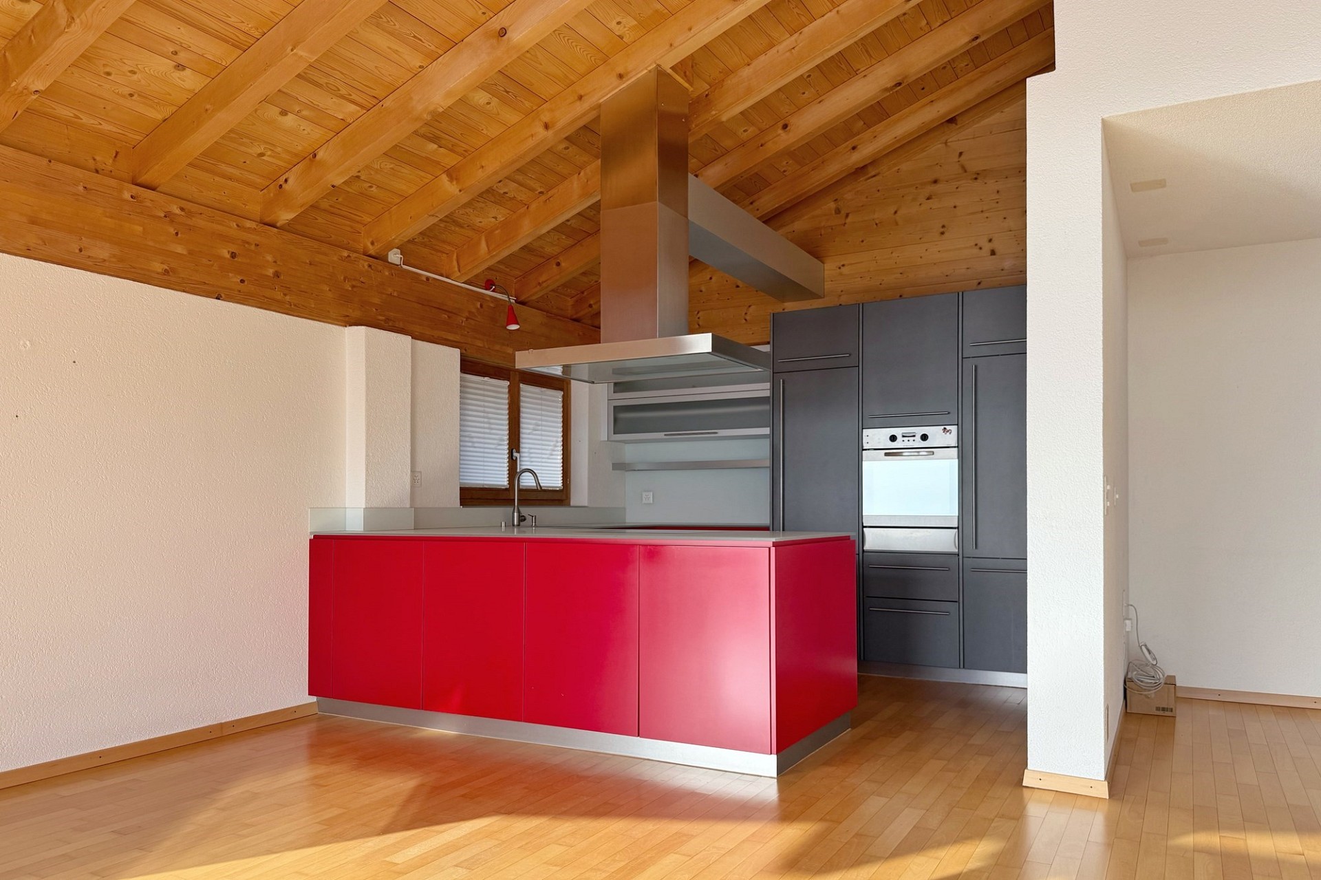 Moderne Küche mit roter Kochinsel und Holzbalkendecke