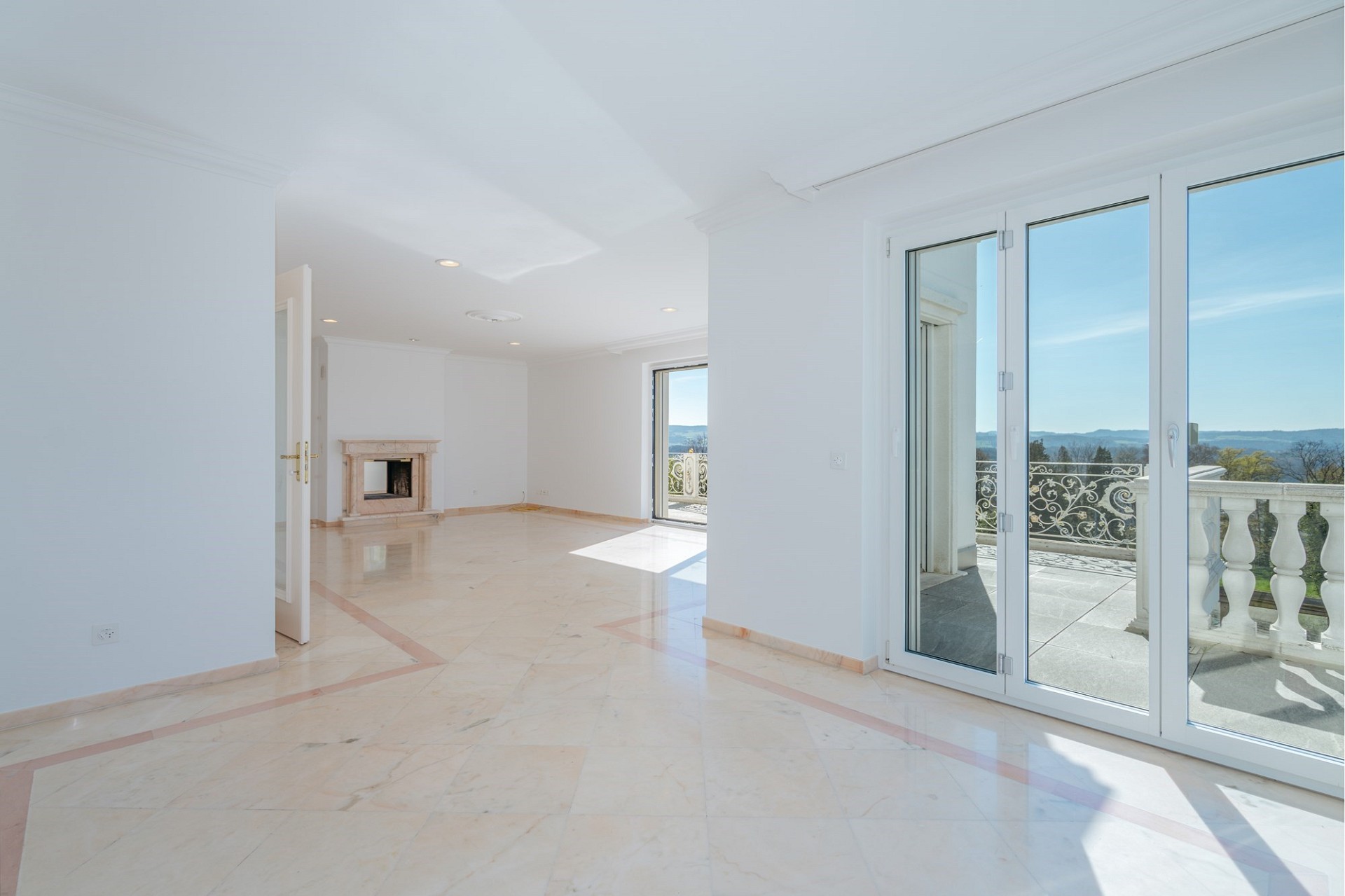 Heller leerer Wohnraum mit Balkon und Kamin