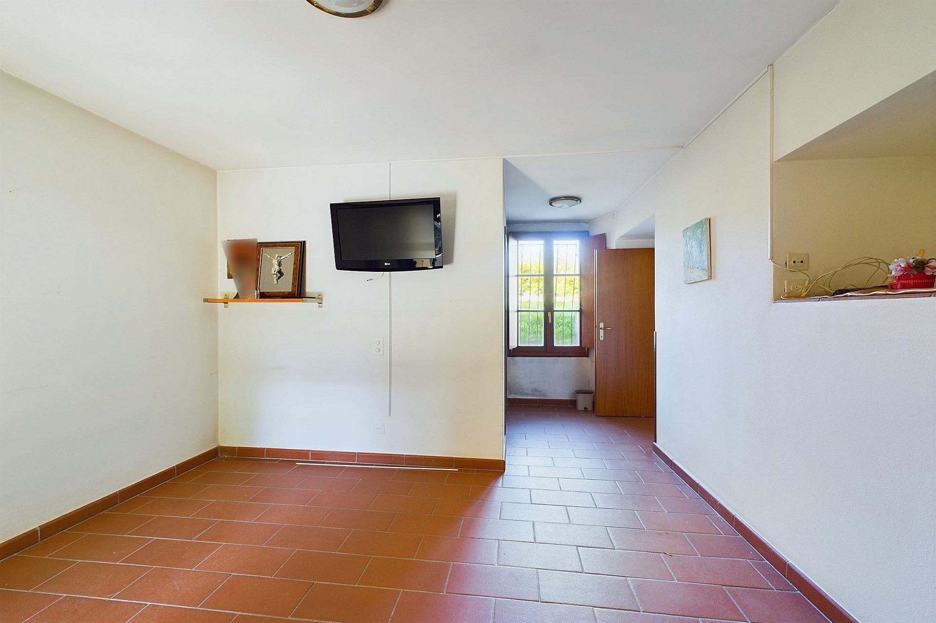 Flur mit Terrakottafliesen und Blick in einen Nebenraum