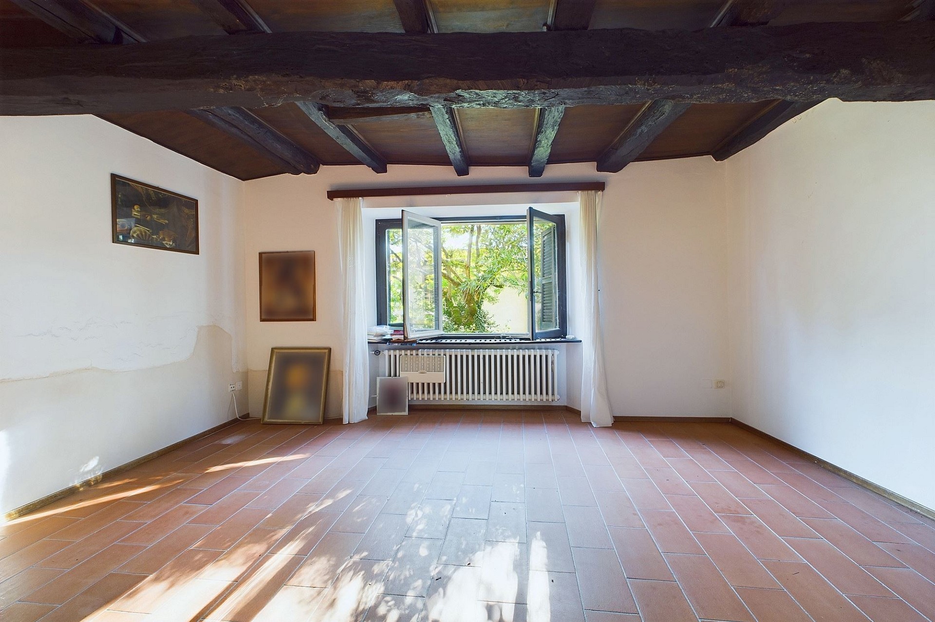 Heller Raum mit Holzbalkendecke und geöffnetem Fenster